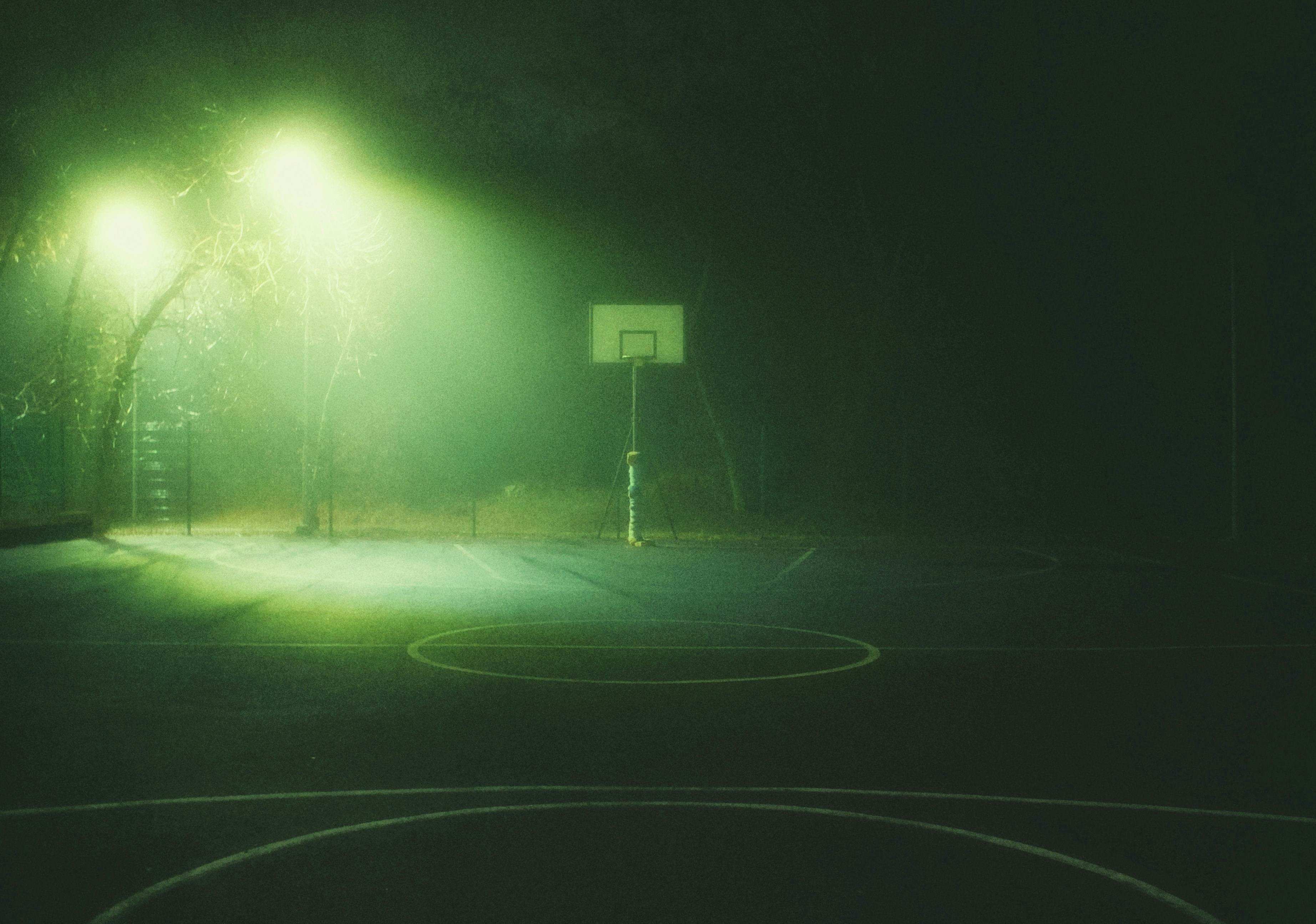 A foggy basketball court illuminated by green lights at night. photo ...