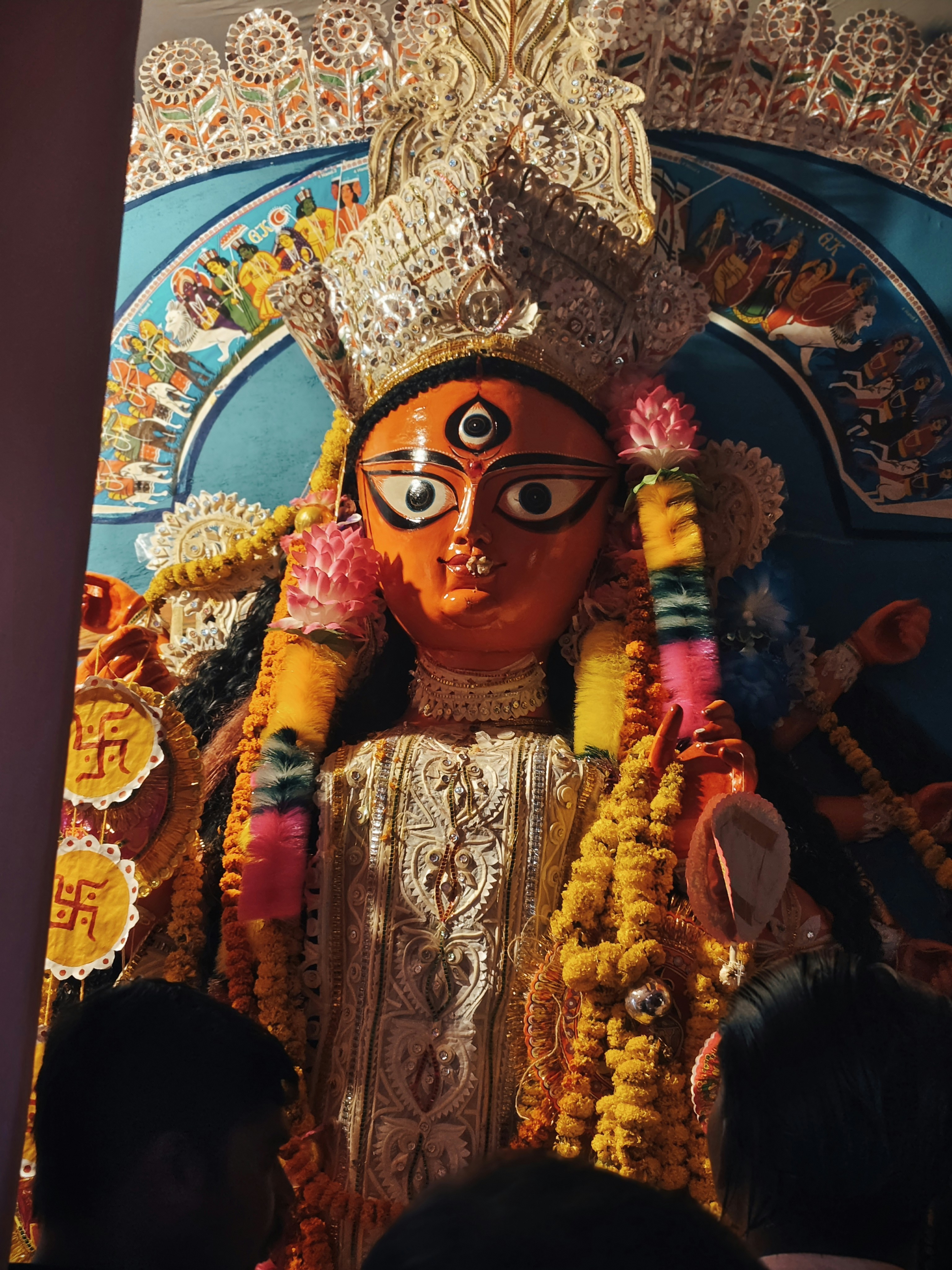Idola durga yang semarak dihiasi dengan karangan bunga dan mahkota.