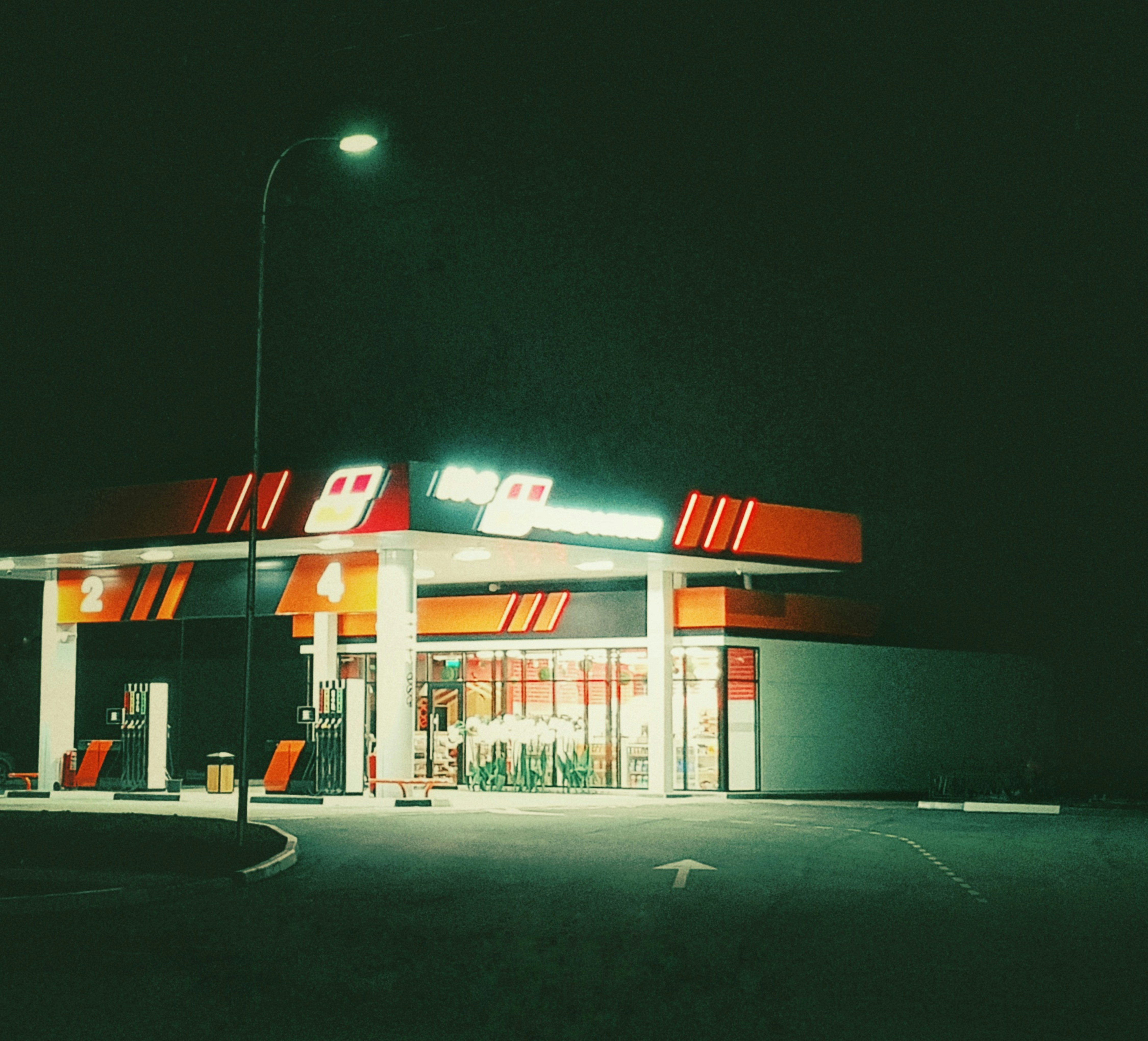 A gas station illuminated at night with dark sky.