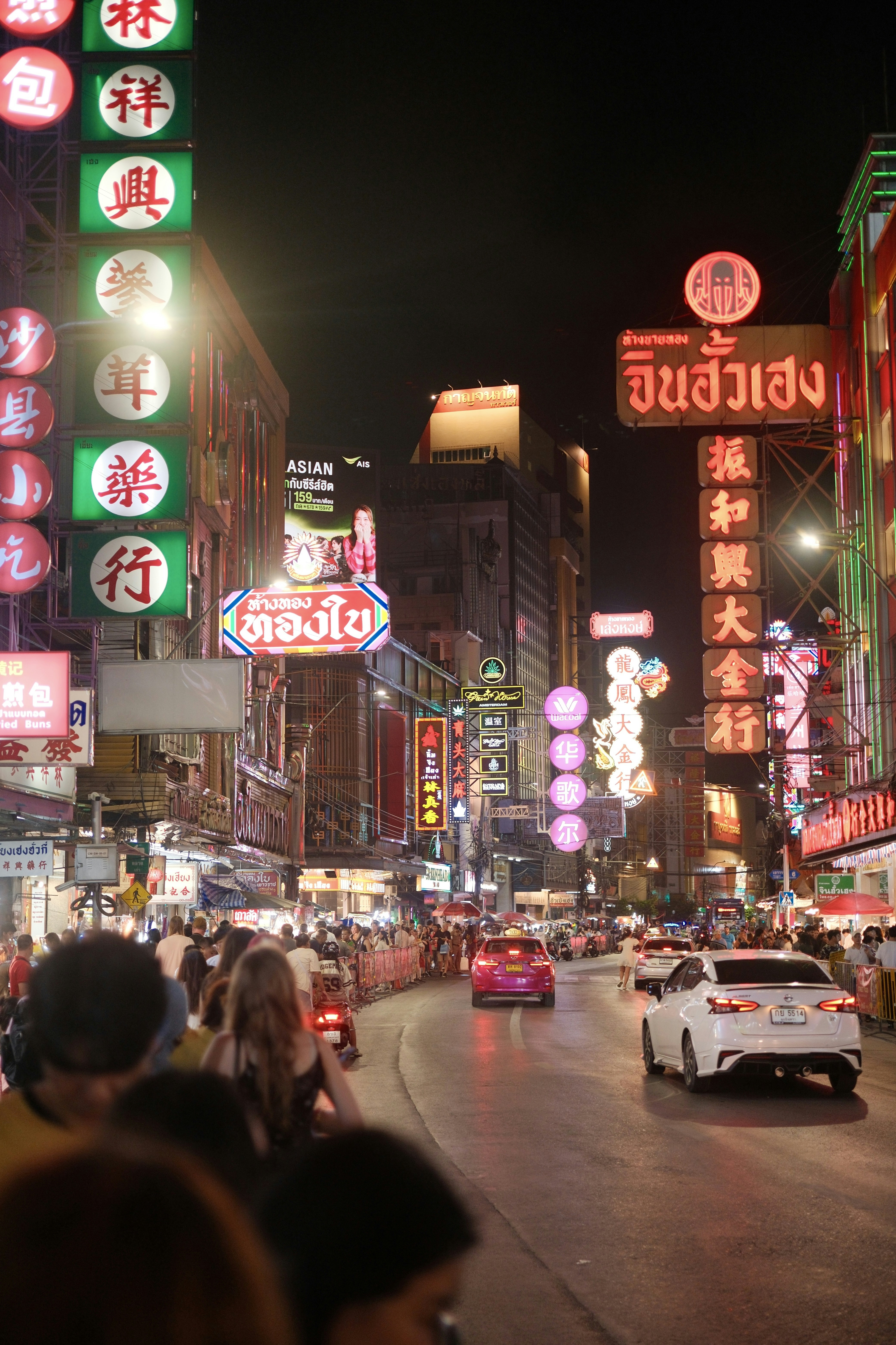 Vibrant chinatown street at night with neon signs and traffic.