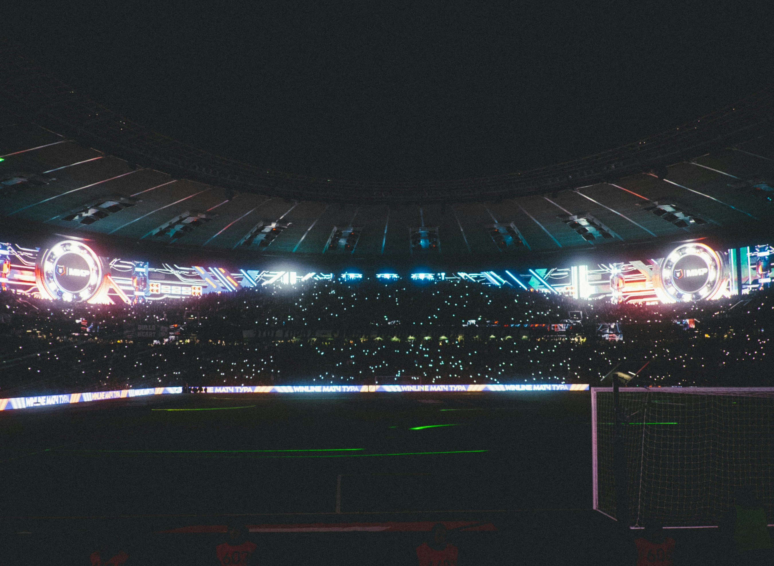 A dark stadium filled with a crowd and bright lights.