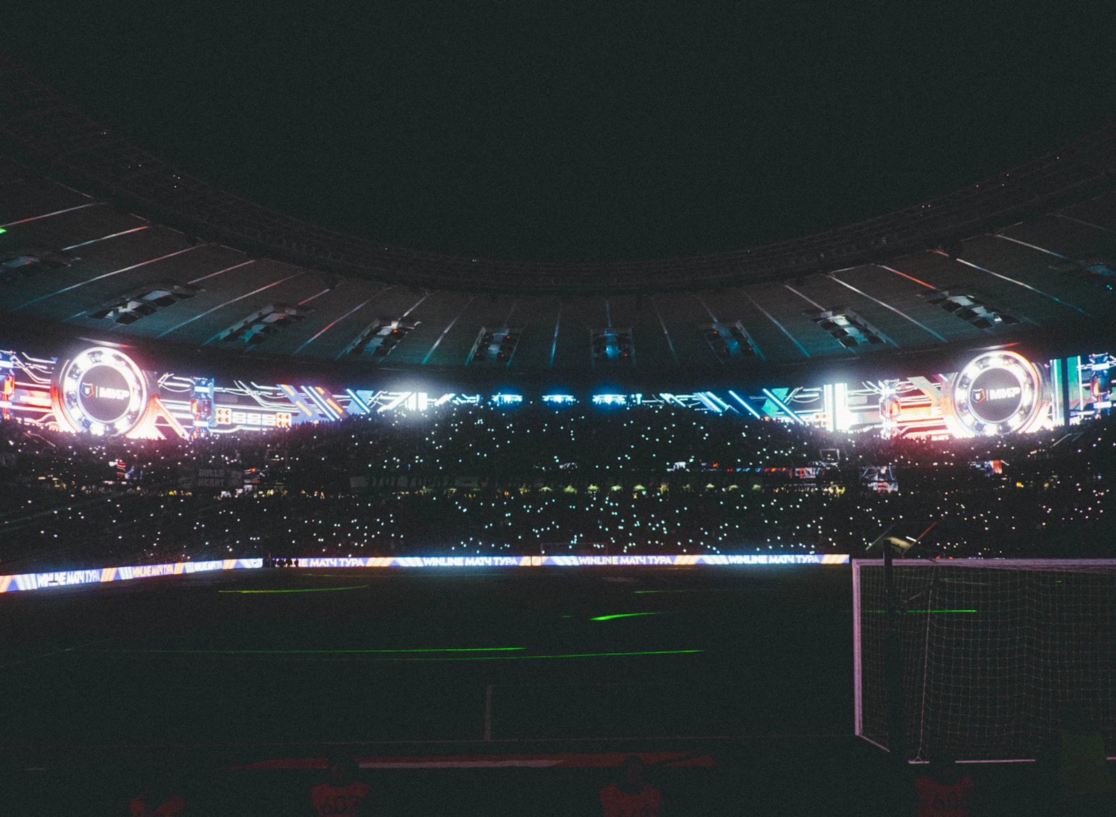 Estádio lotado à noite, iluminado por luzes e telões