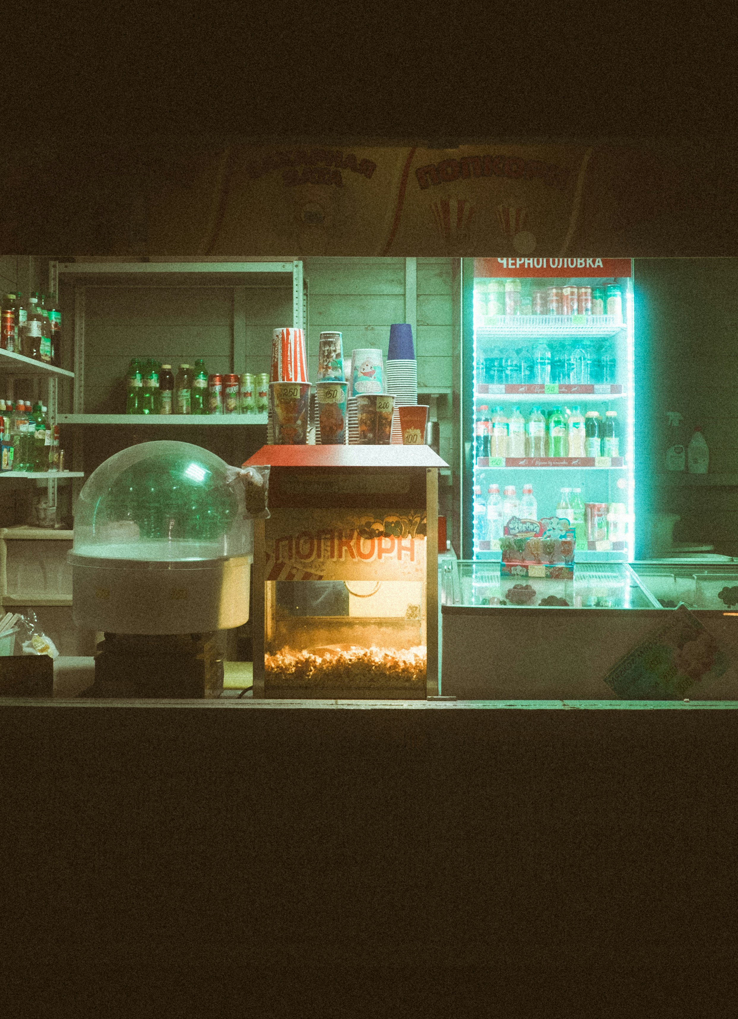 Concession stand with popcorn machine and glowing drink cooler.