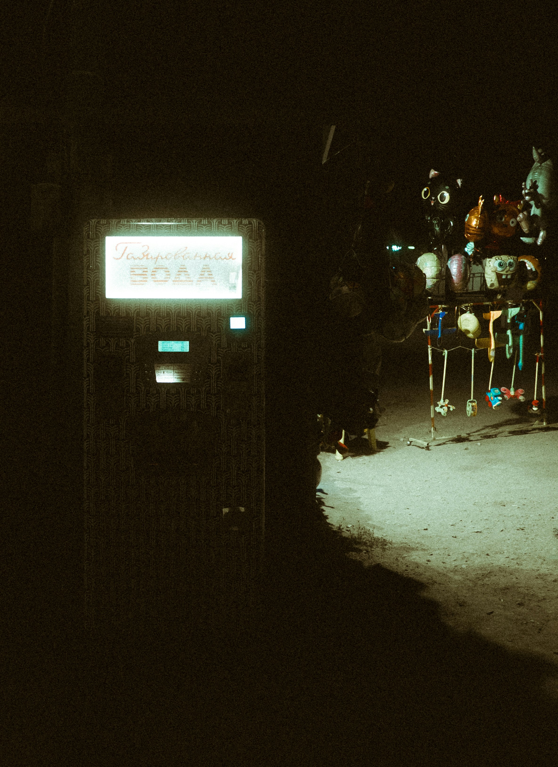 A glowing machine and a stand of items at night.