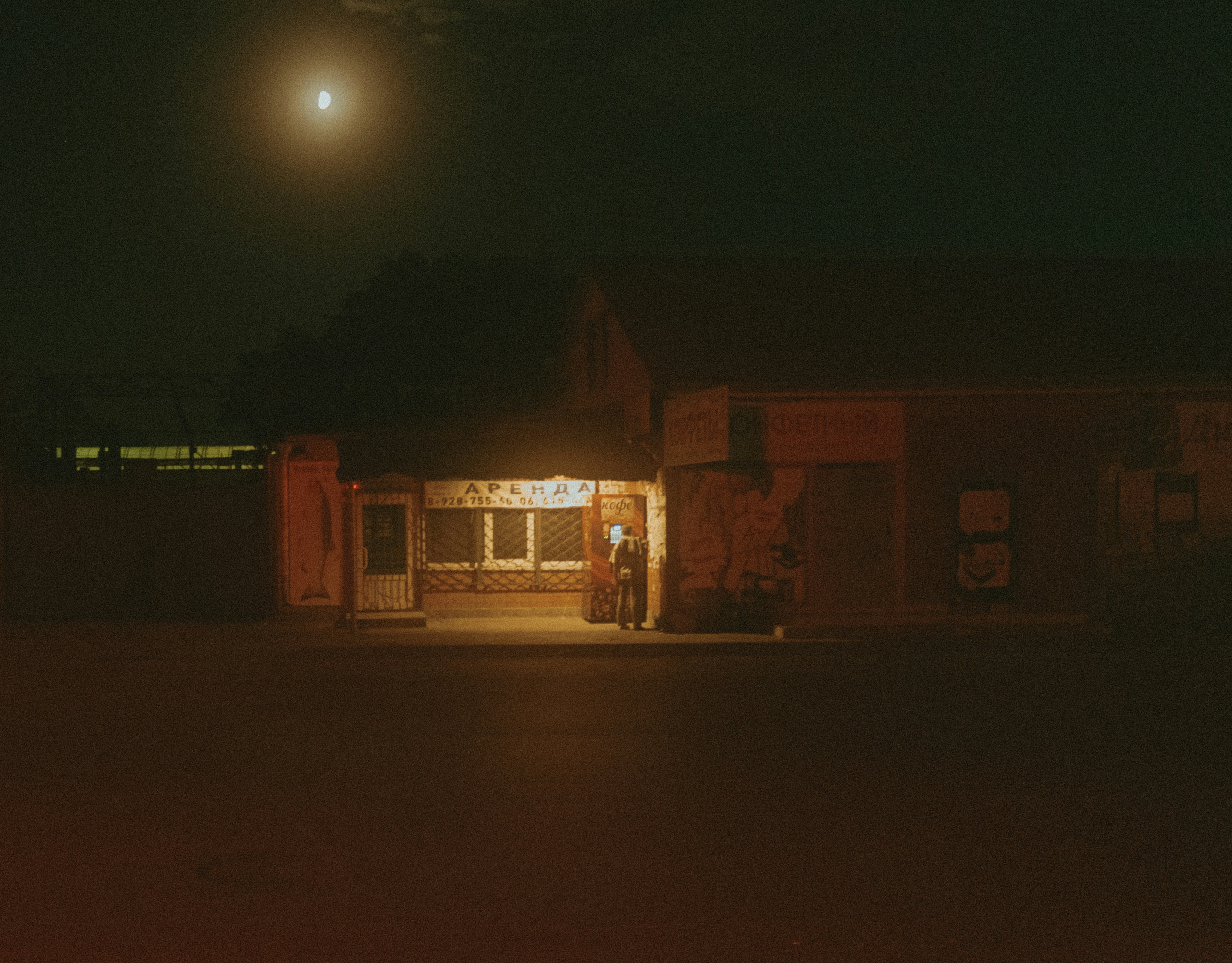 A dimly lit building under a full moon at night.