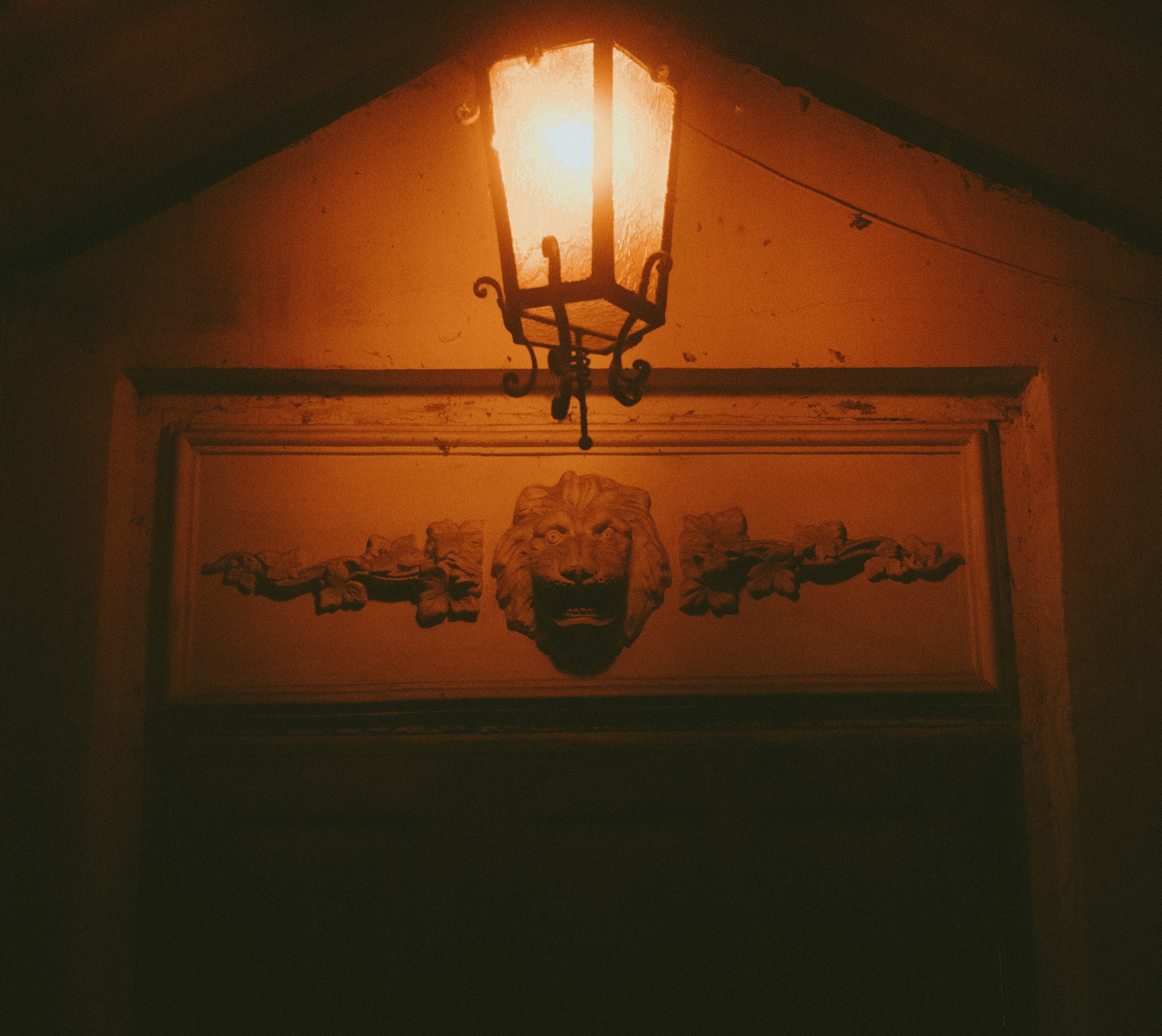 Warm lantern light illuminates a decorative lion head carving.