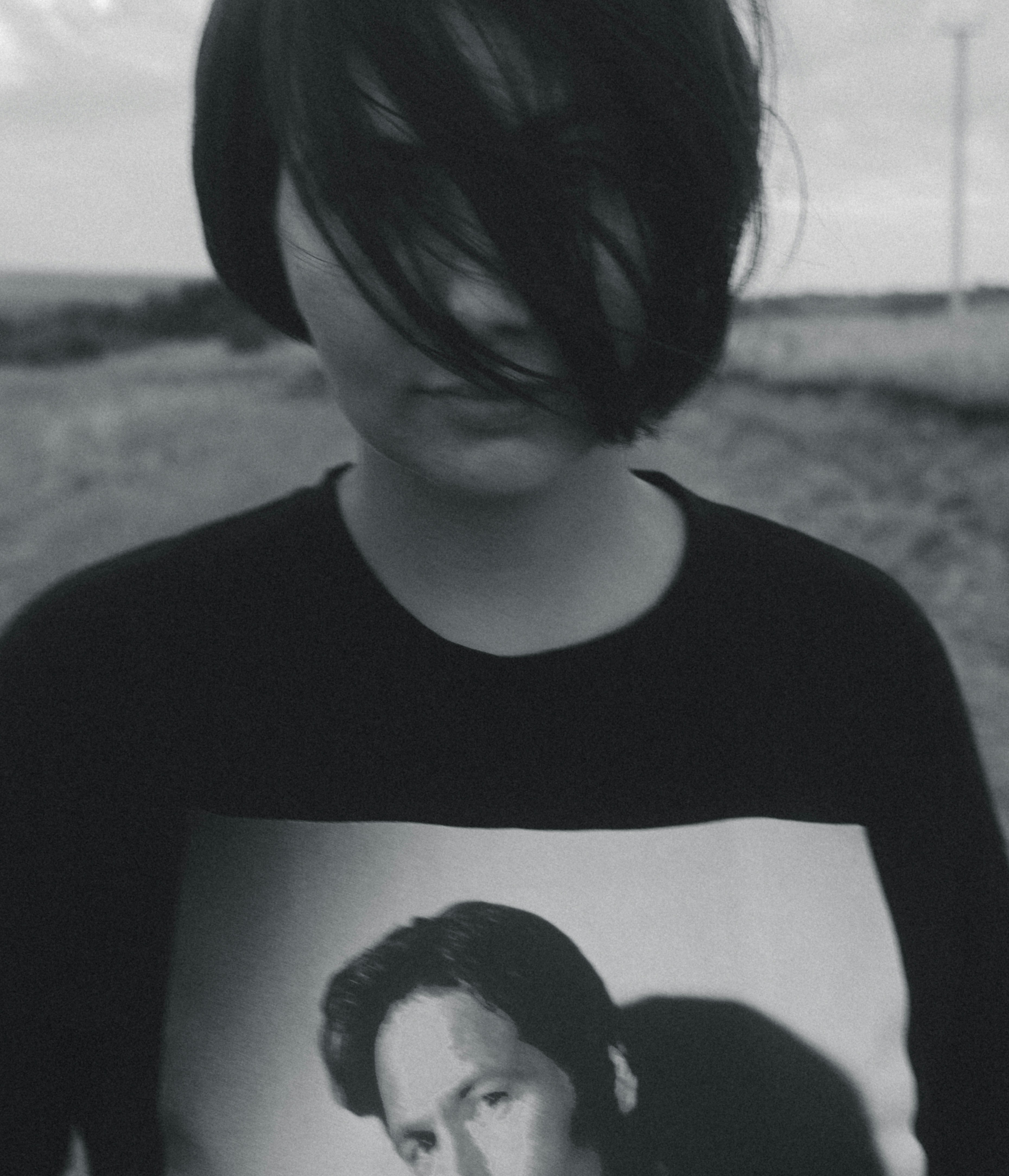 Dark-haired person with face obscured, wearing a graphic t-shirt.