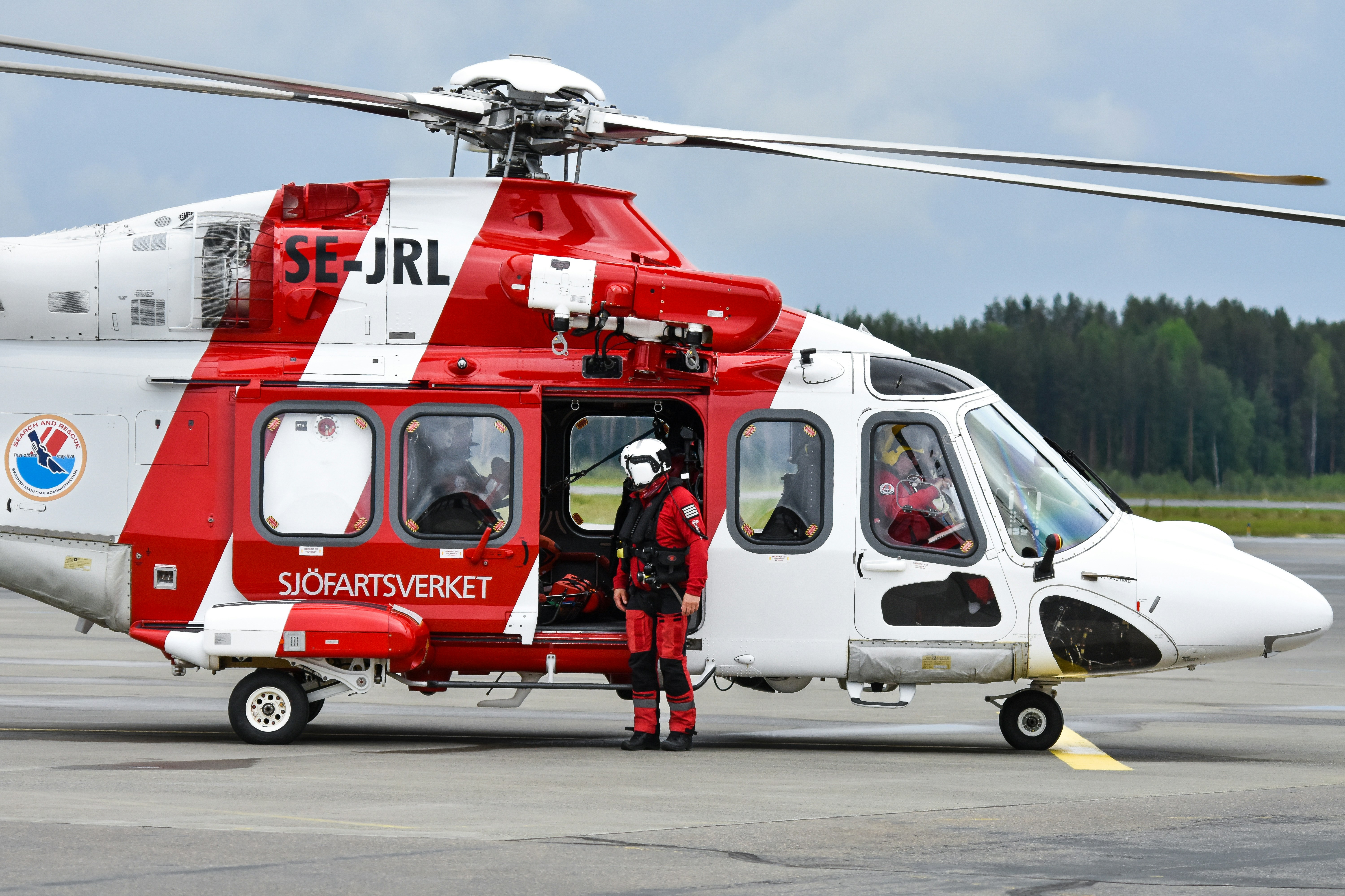 A rescue worker stands by a red and white helicopter.