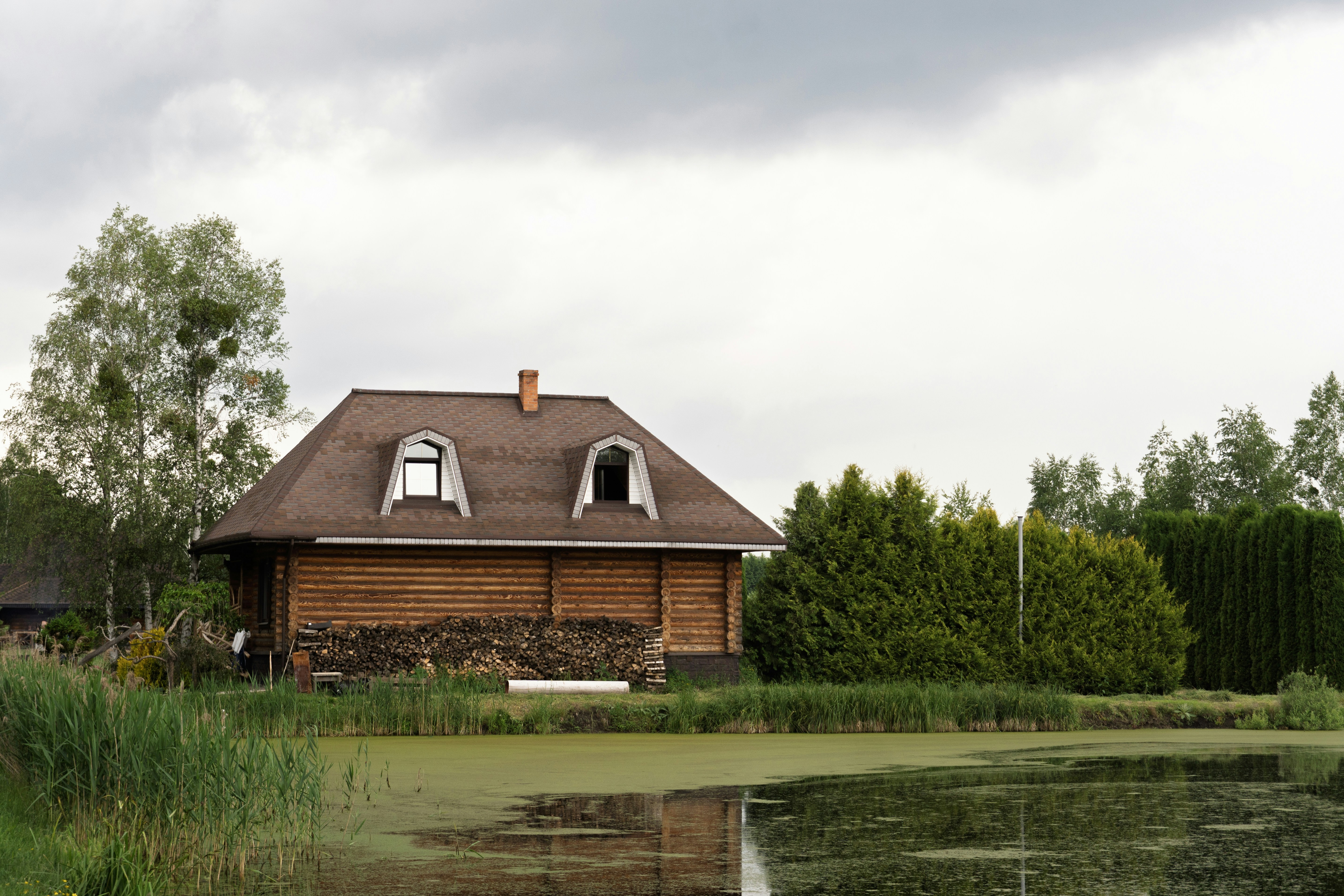A cozy wooden house beside a tranquil pond.