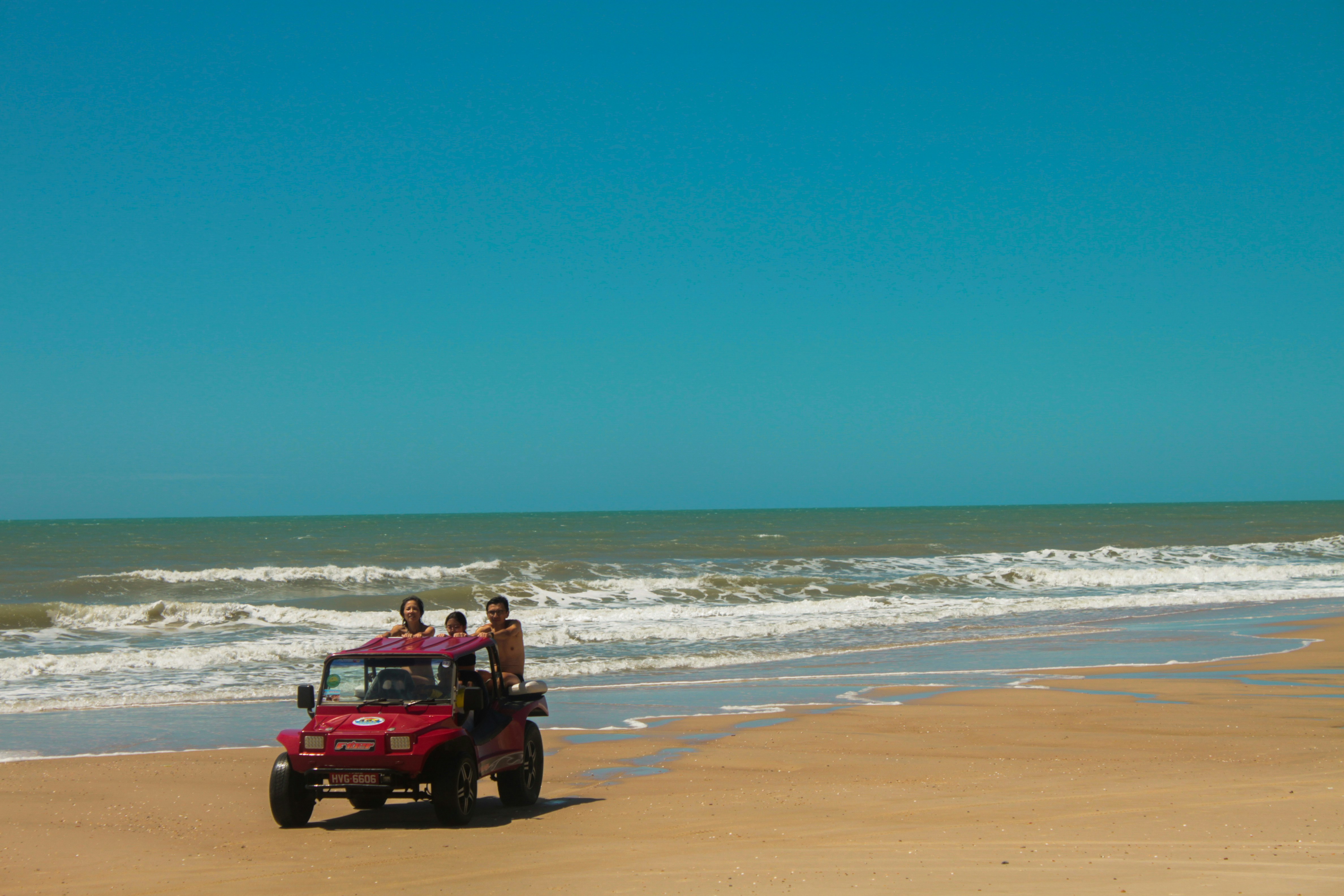 A red dune buggy driving along a sandy beach