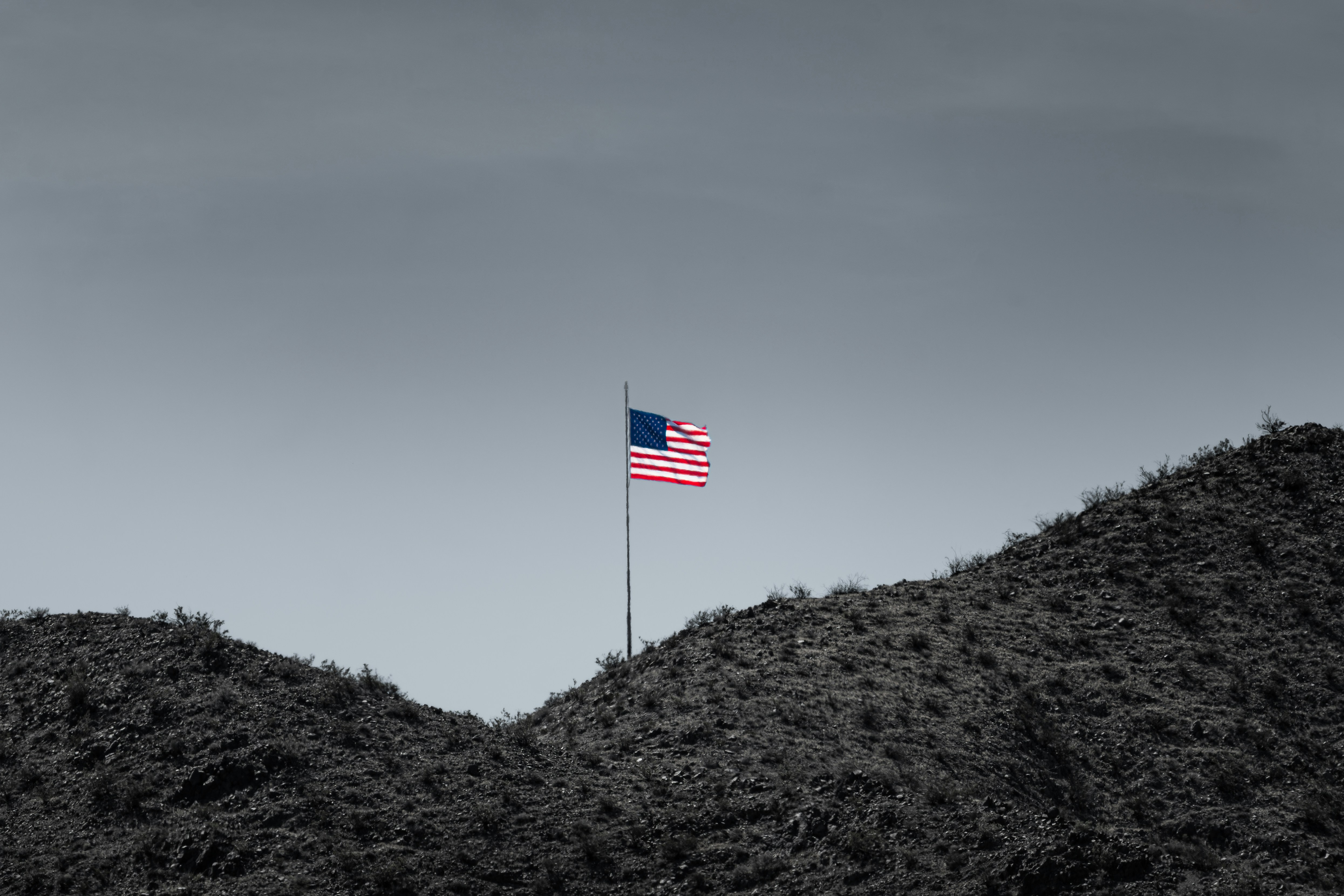 American flag in color on a monochrome landscape.