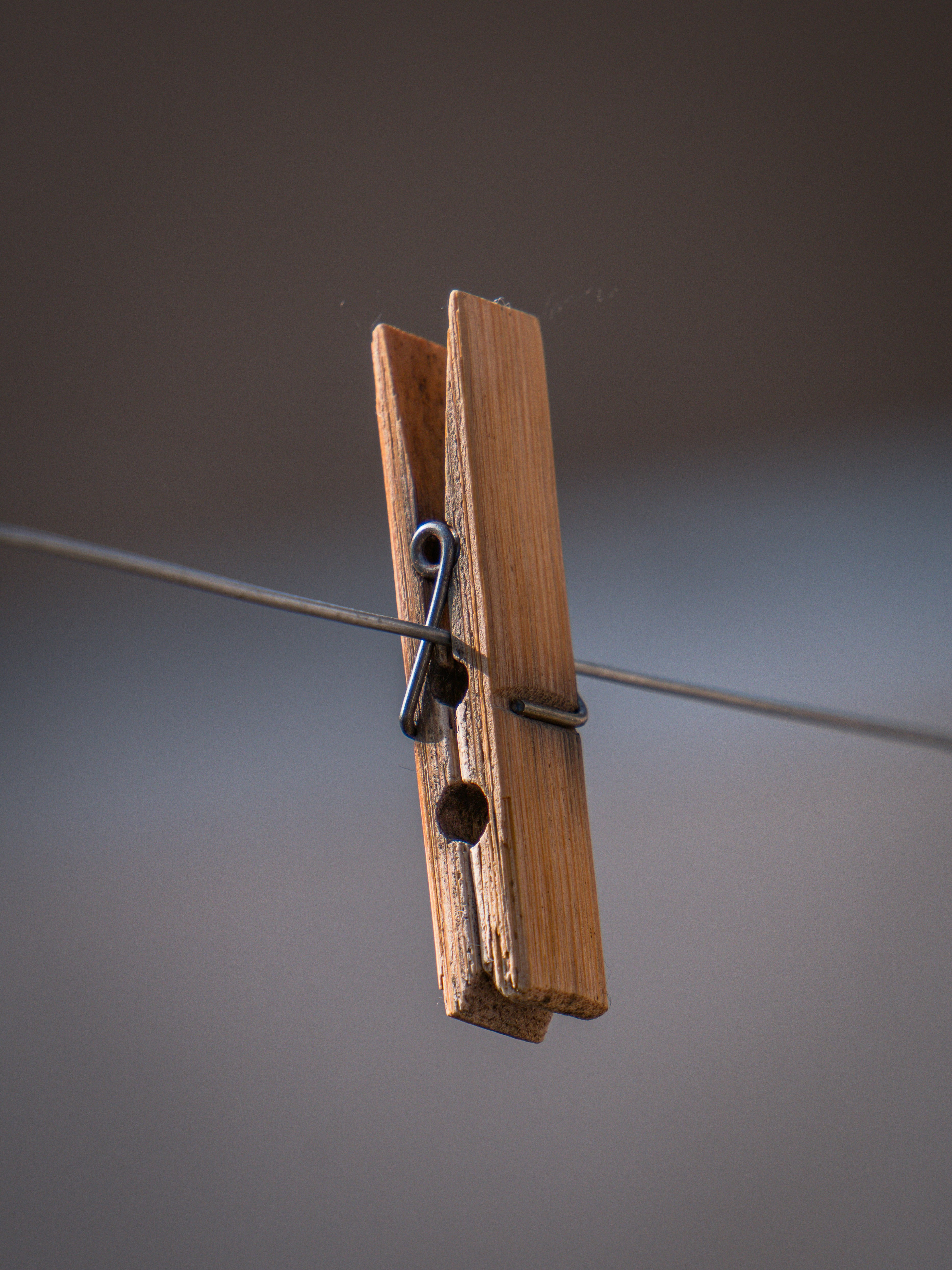 A wooden clothespin hangs on a thin wire.