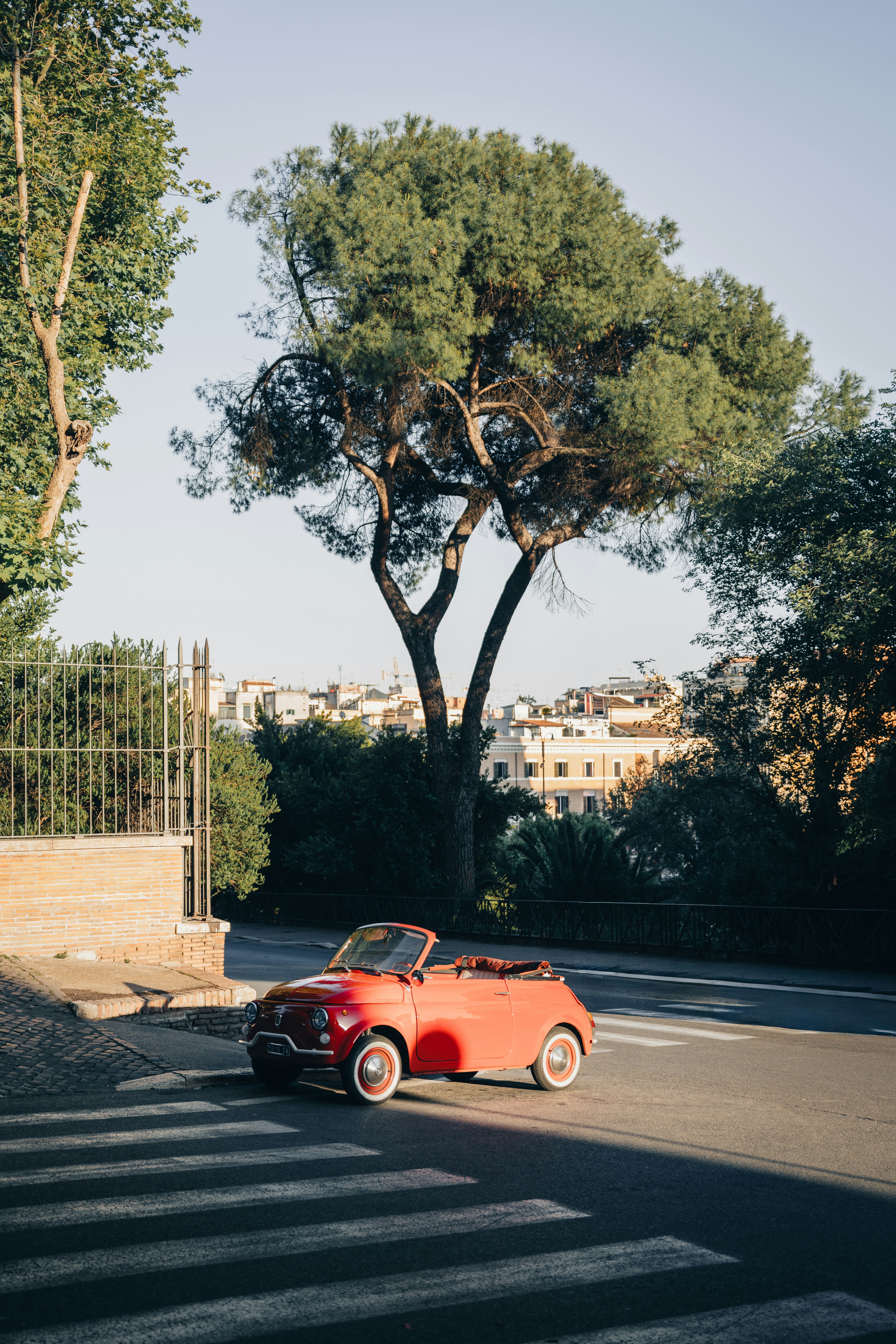 Vintage red convertible car parked on a sunny city street.
