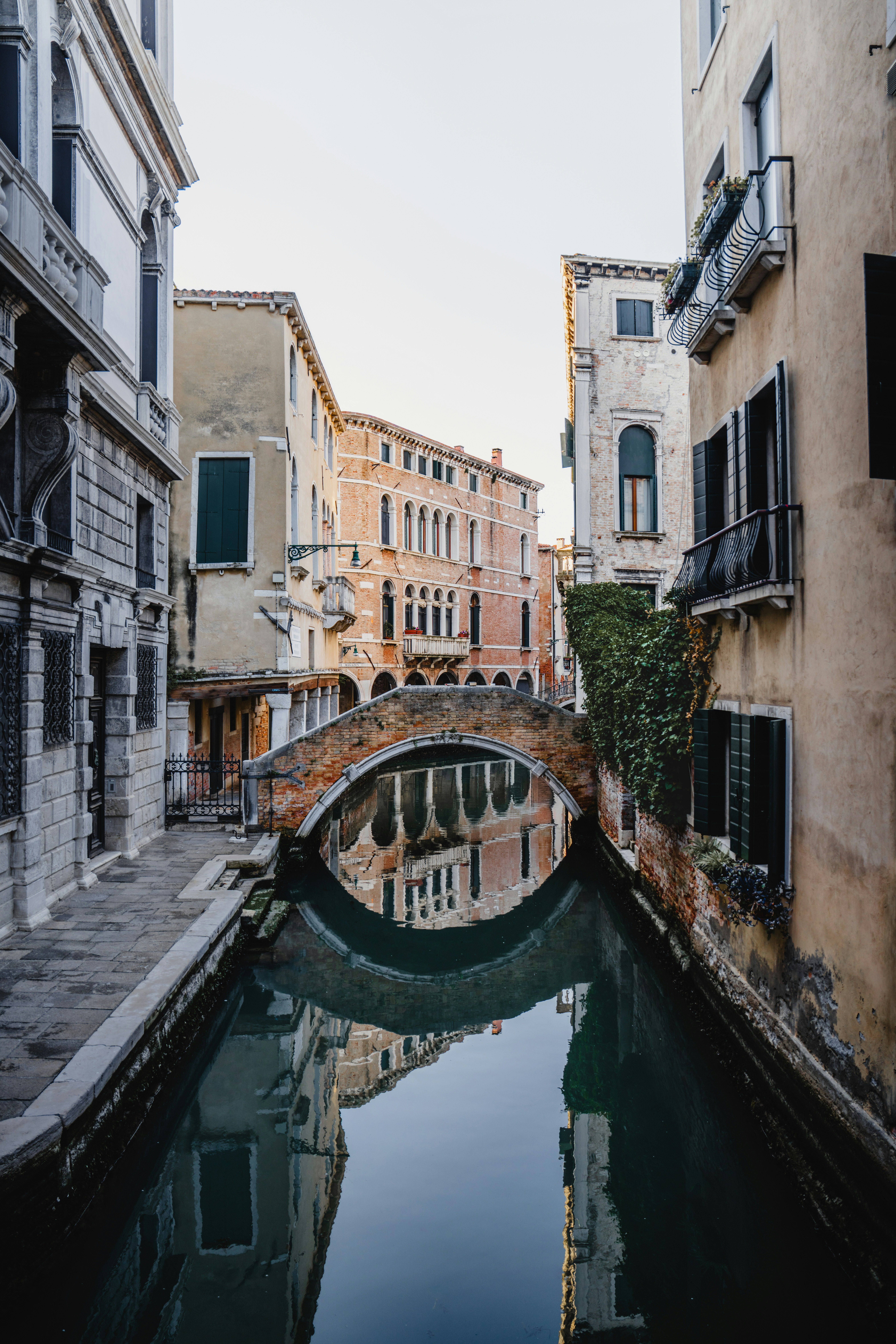 Historic venetian canal with arched bridge and building reflections.