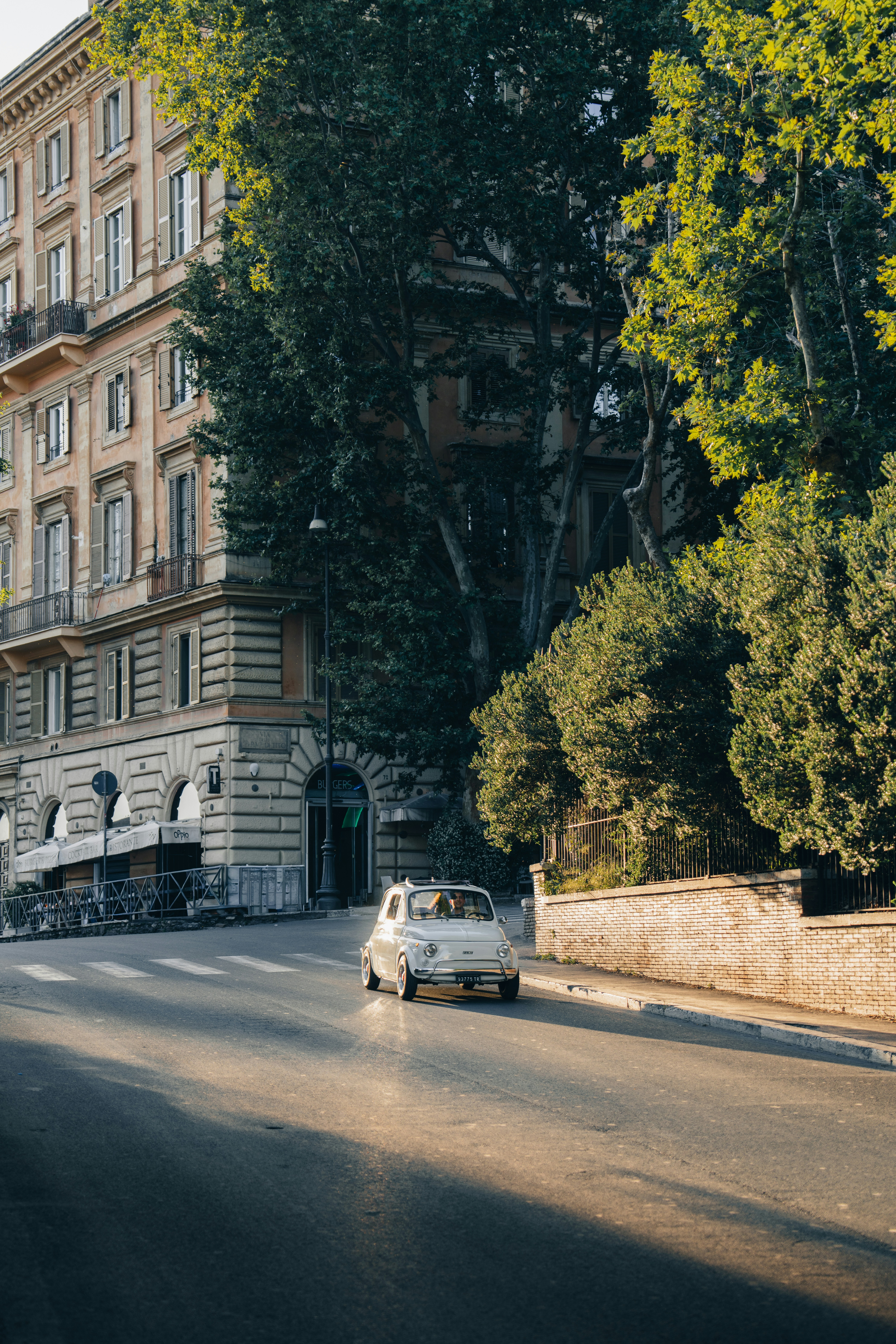 Classic white car on a sunny street with historic buildings.