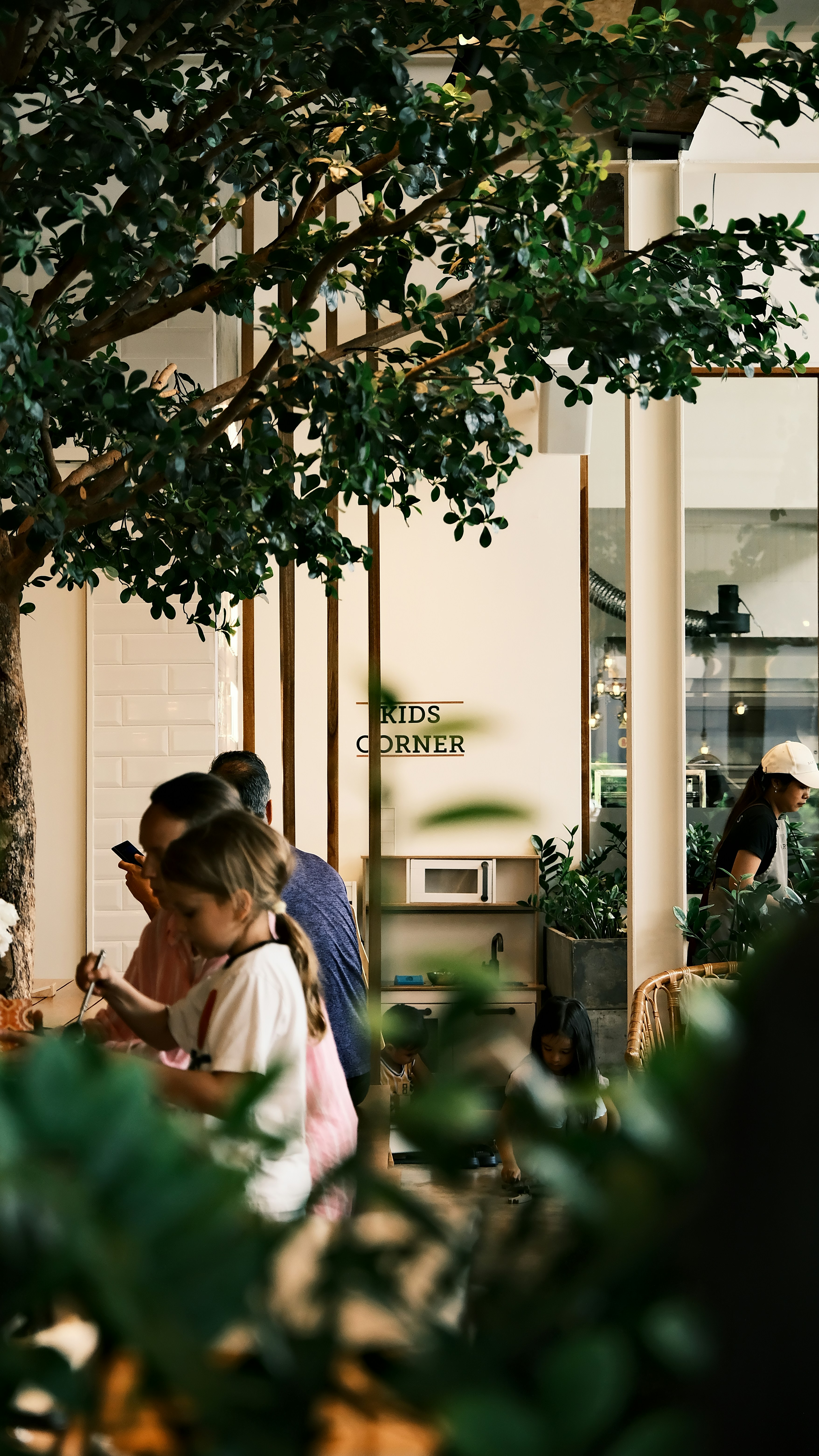 Kids playing in a cafe's "kids corner" with greenery.