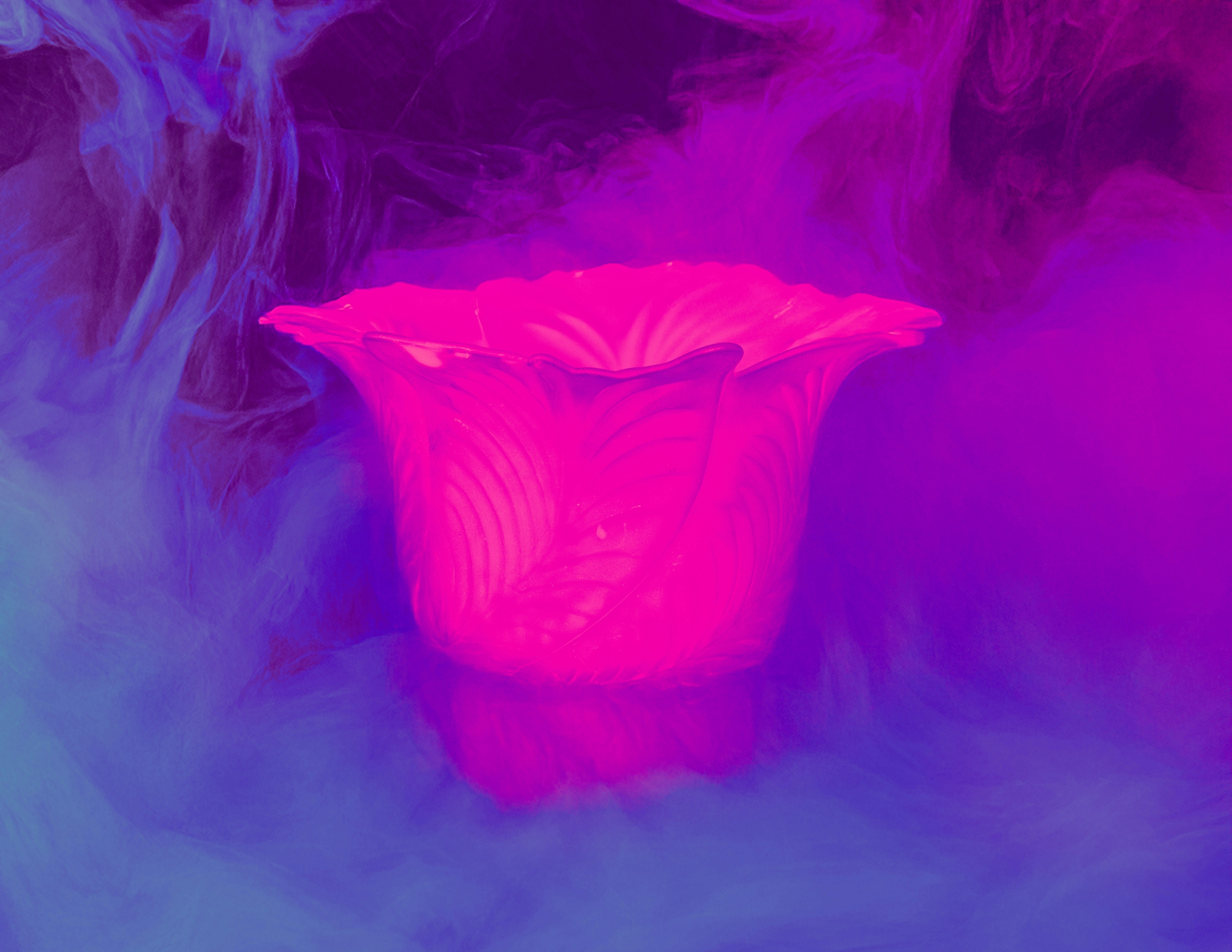 Vibrant pink object glowing amidst blue and purple smoke.