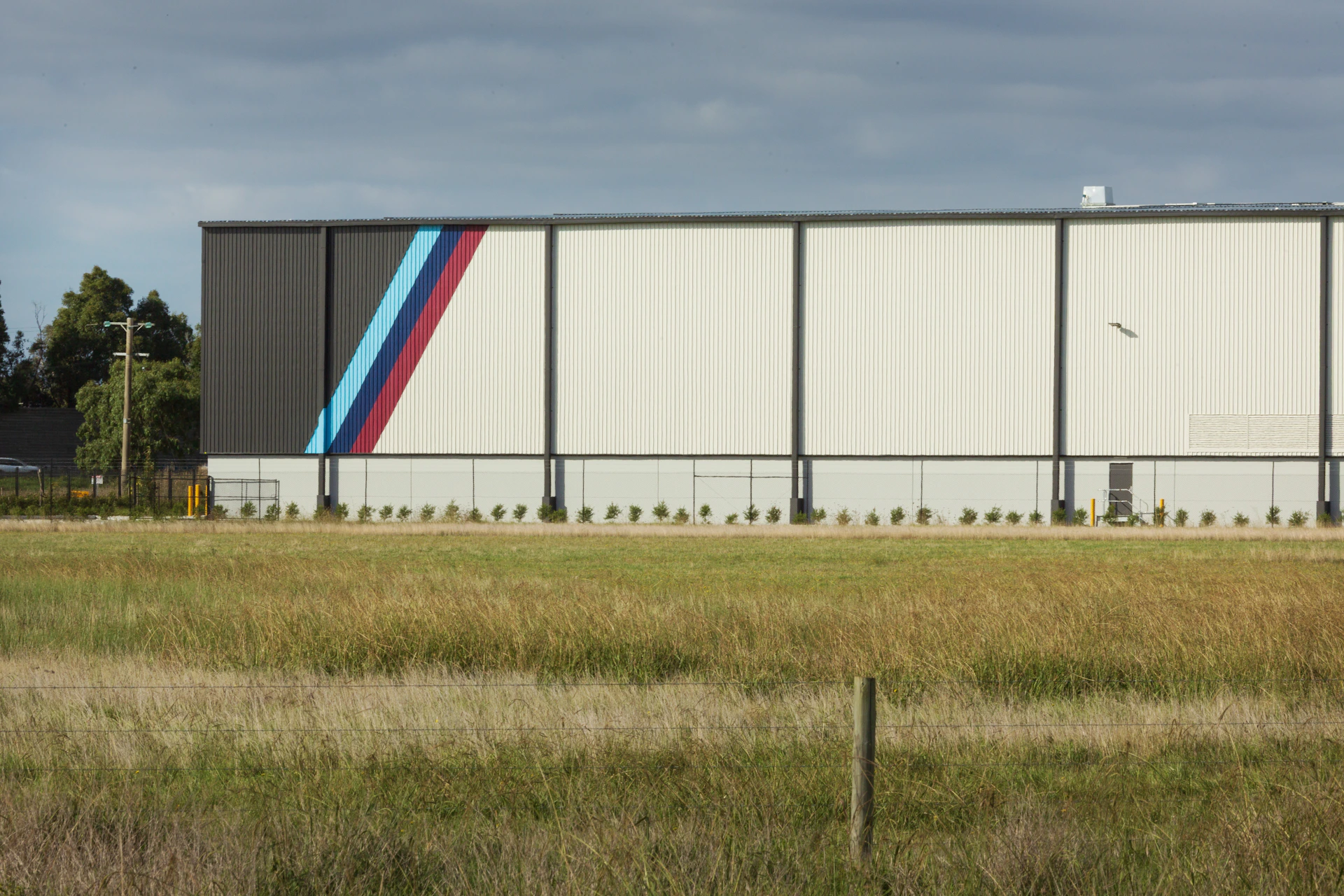 Modern building with blue, purple, red stripes and a field.