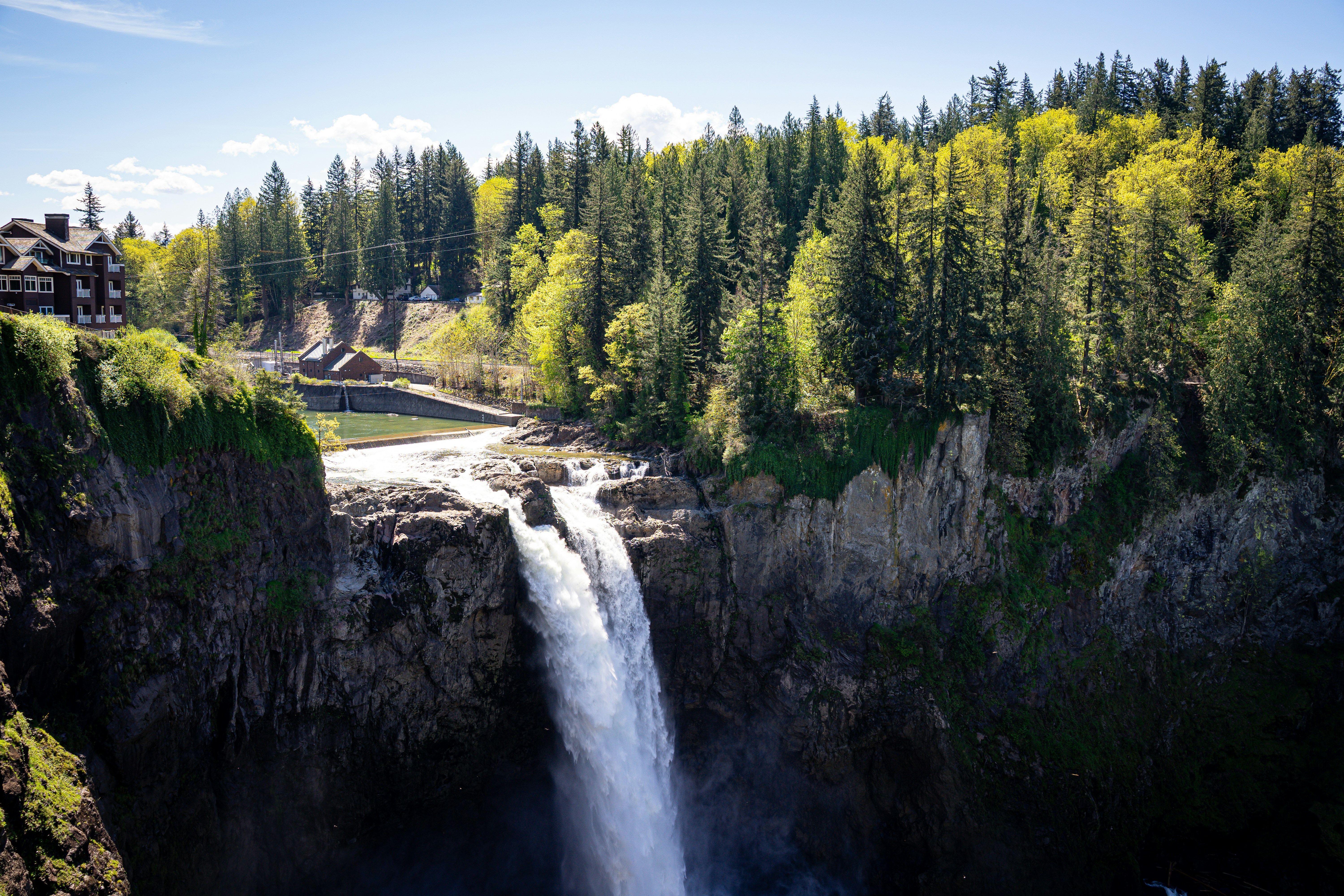 Powerful waterfall cascades down a cliff surrounded by lush forest.