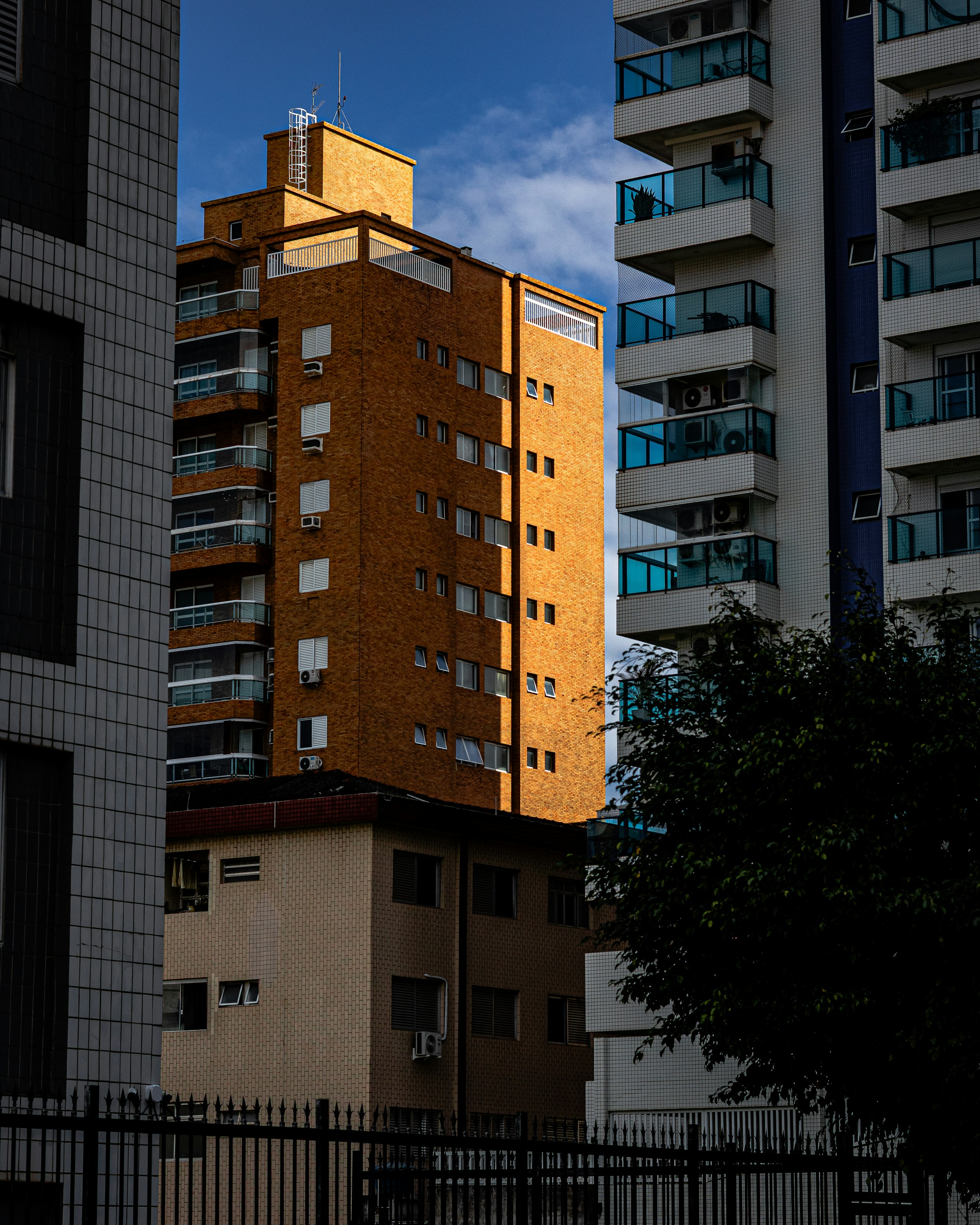 Sunlight illuminates a tall brick building among urban structures.