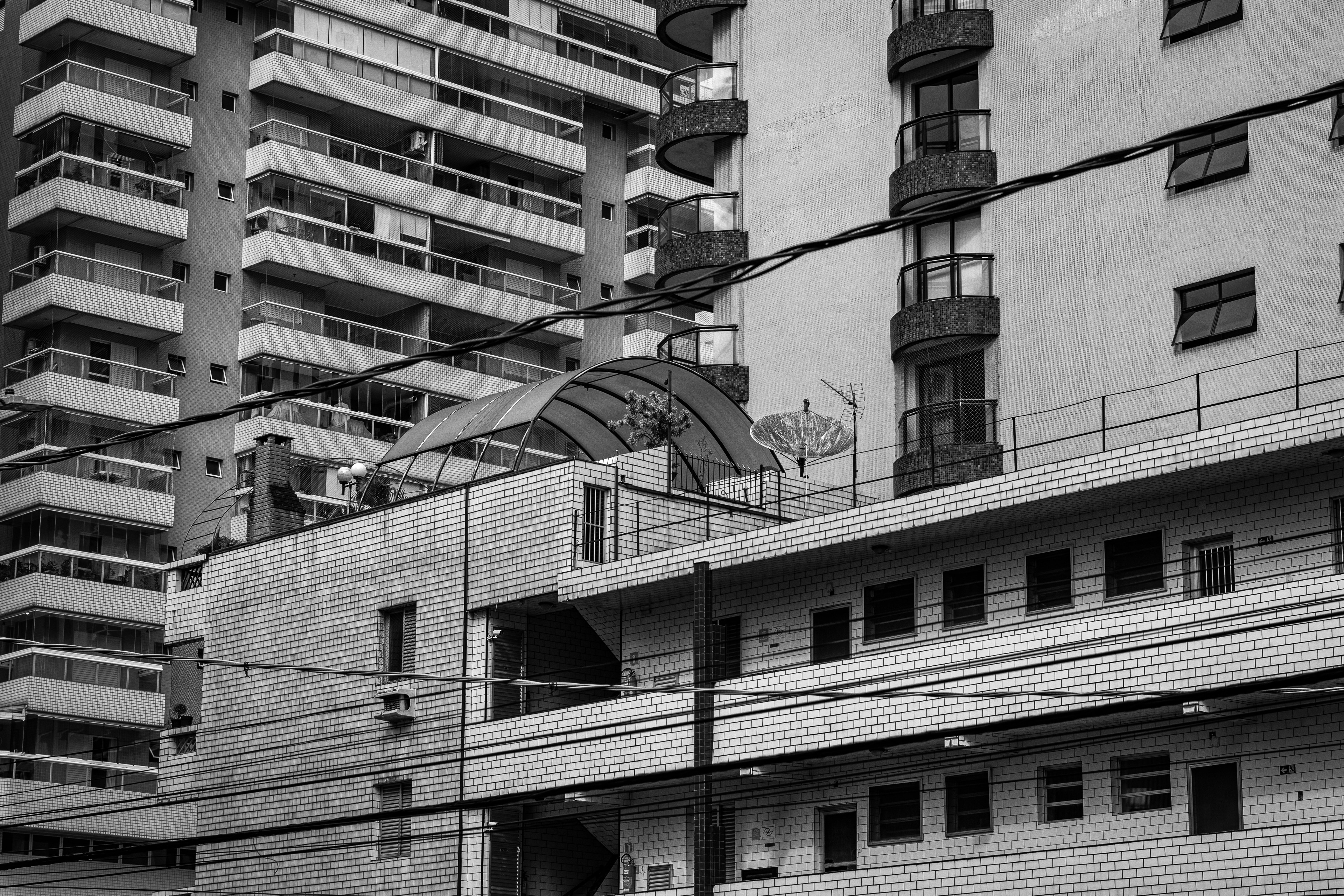 Black and white urban buildings with numerous power lines.