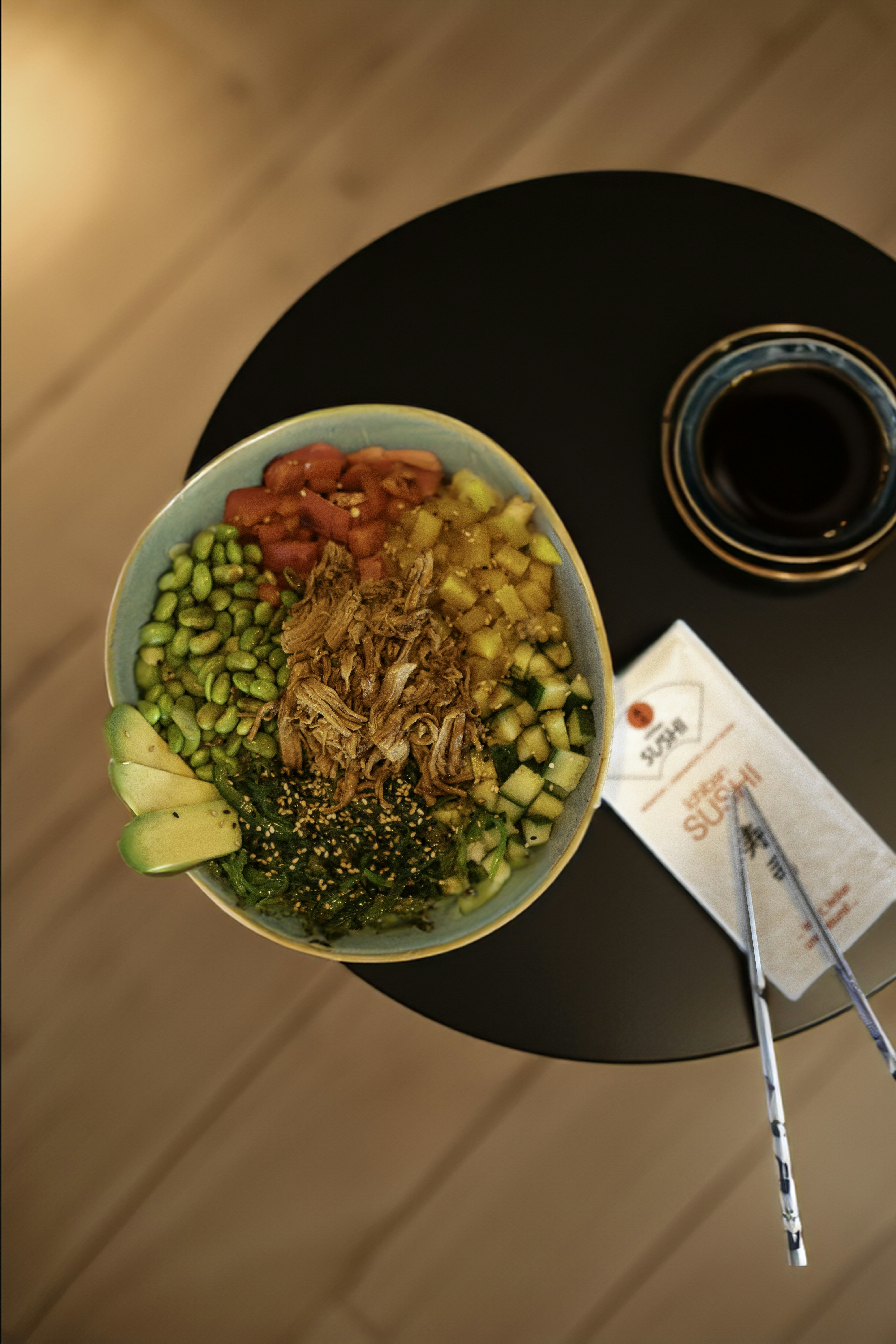 Delicious poke bowl with fresh vegetables, meat, and soy sauce.