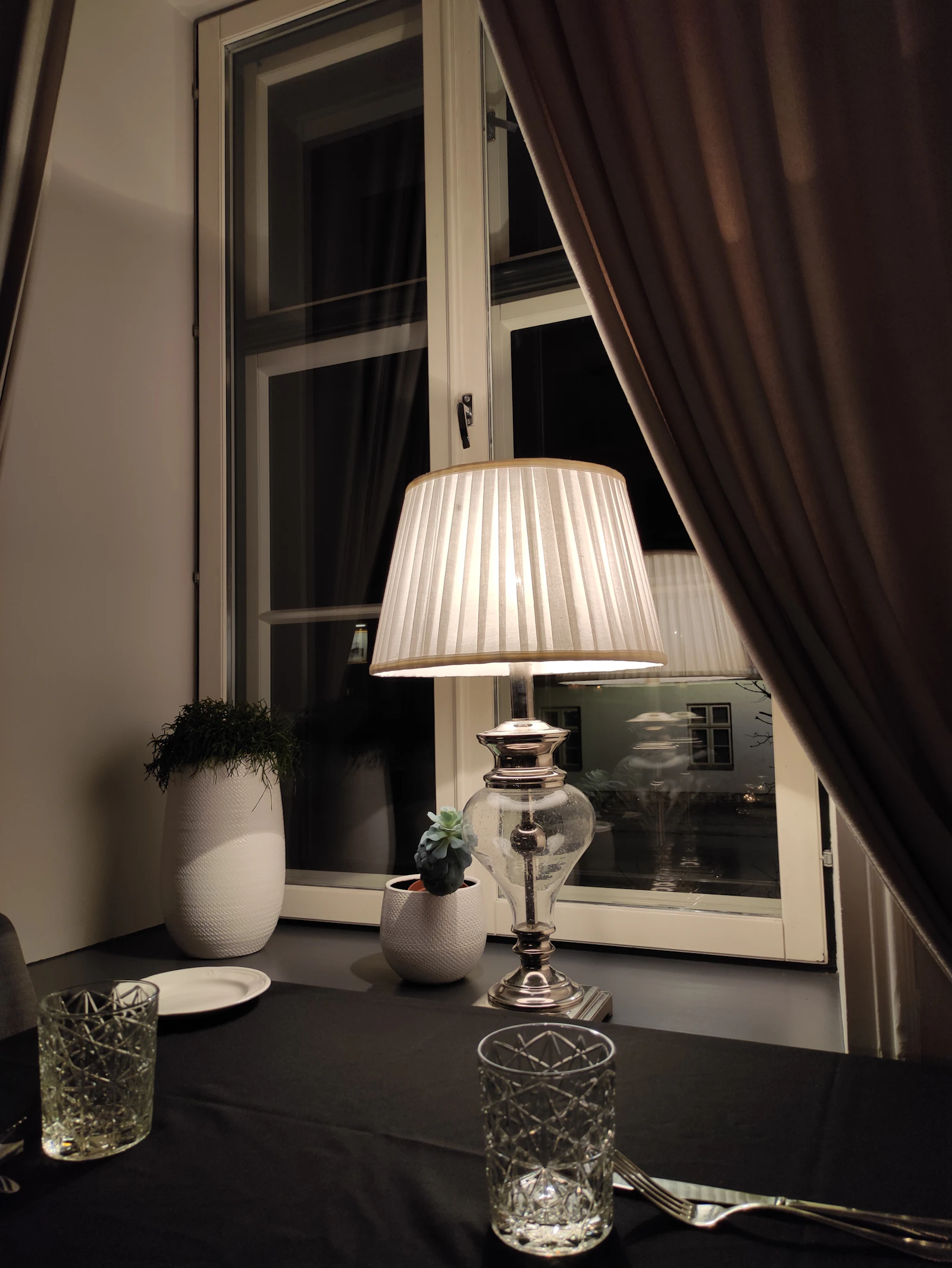 A lamplit table beside a window at night