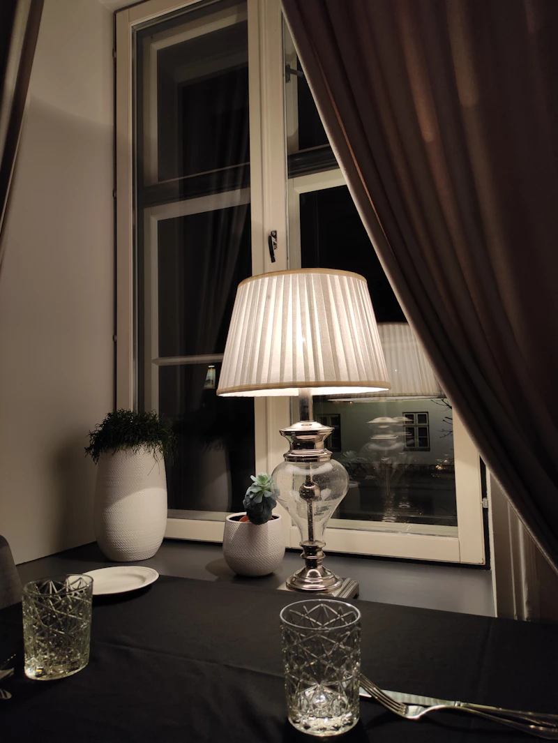 A lamplit table beside a window at night