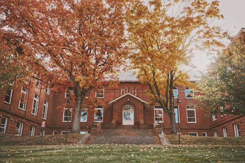 Old brick building surrounded by vibrant autumn foliage.