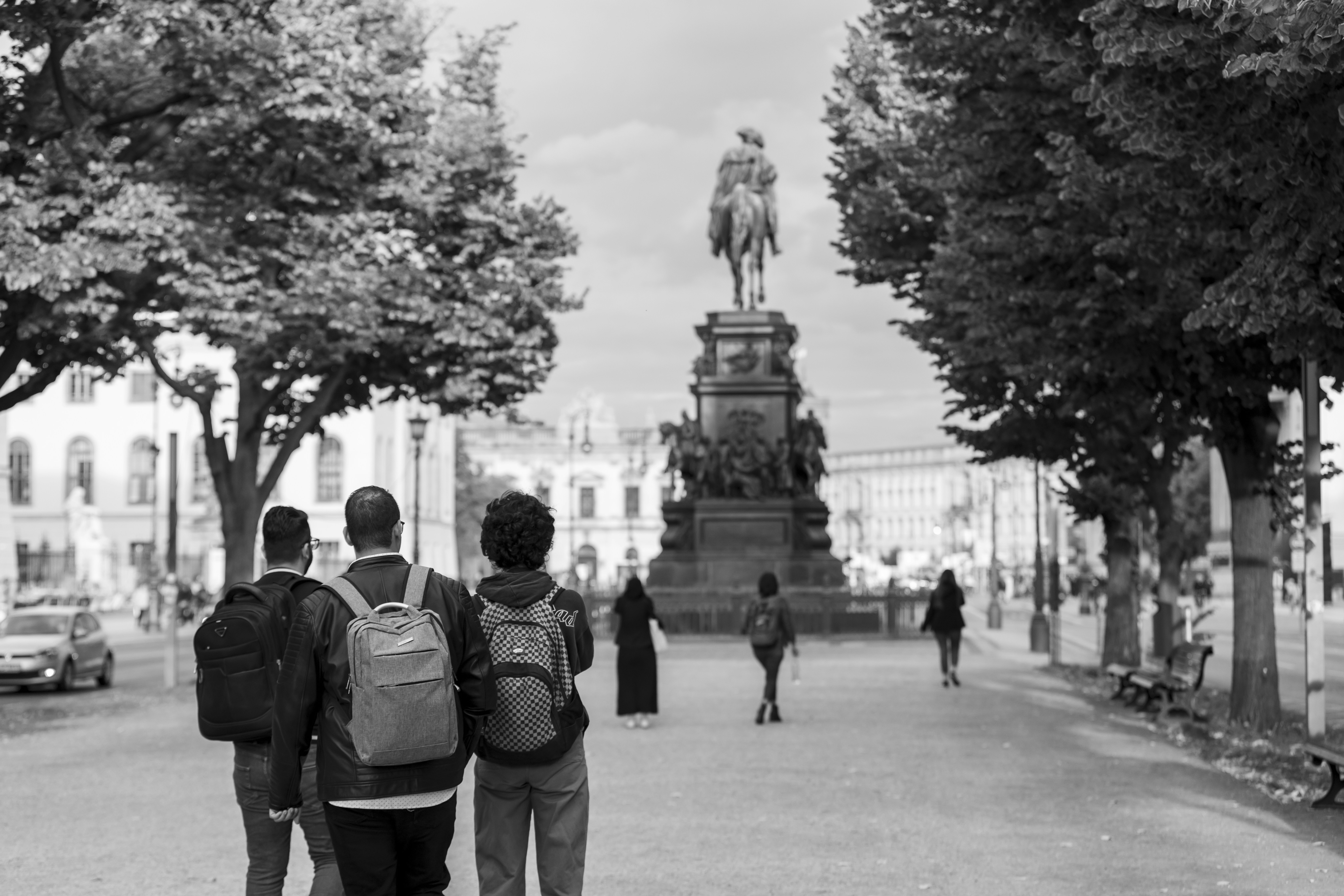 Three people walk towards a large equestrian statue.