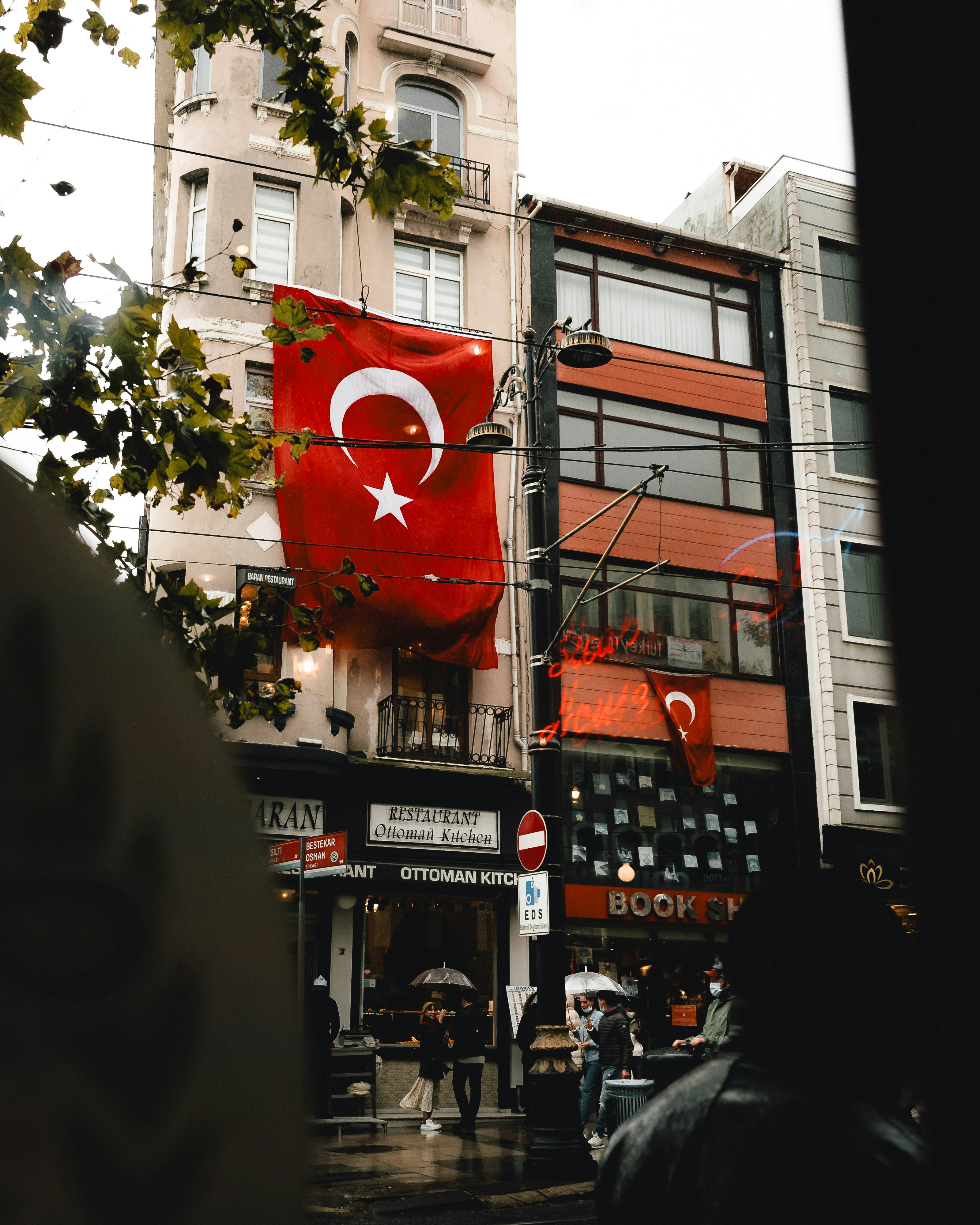 Turkish flag on a city building above a wet street.