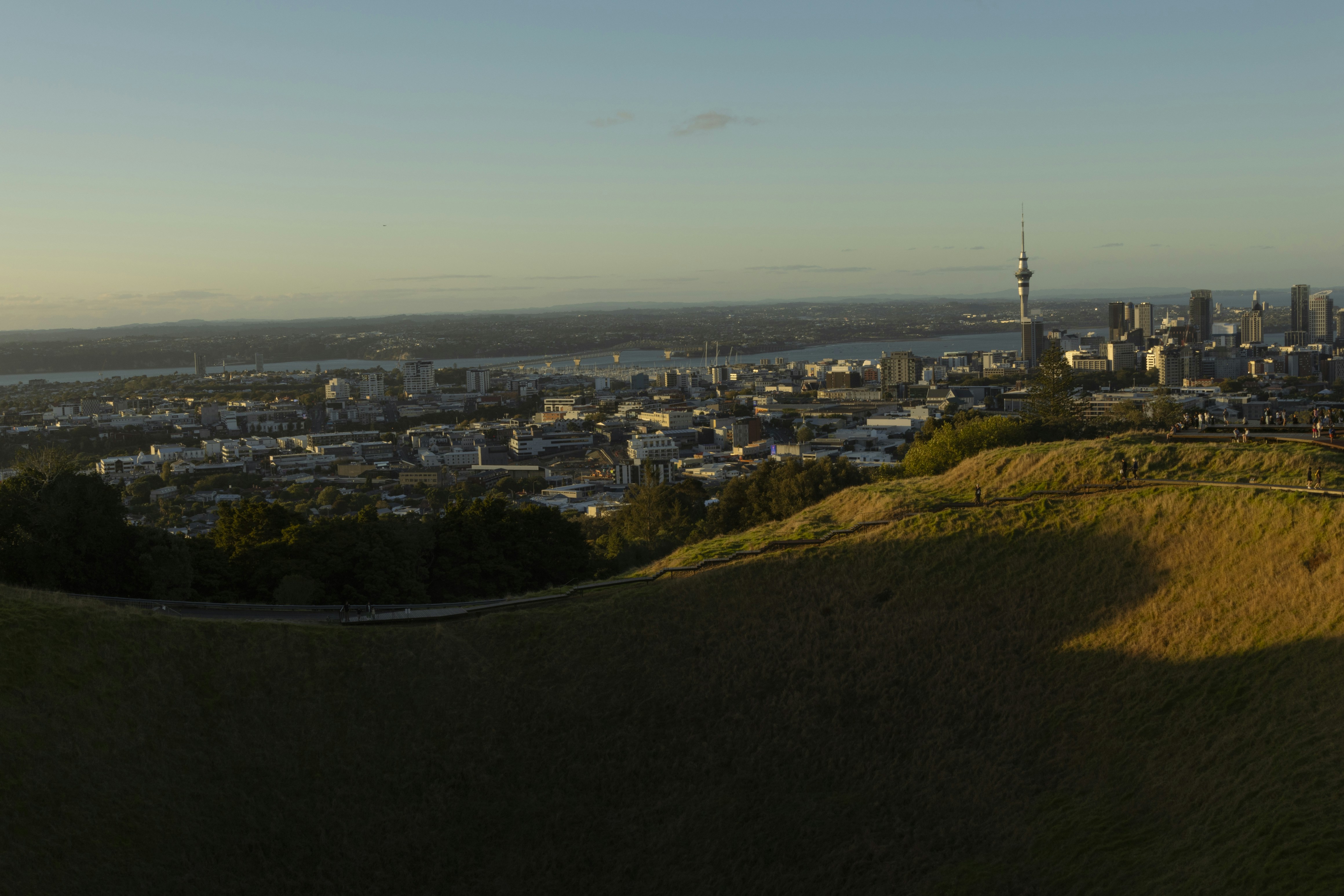 New Zealand residential houses suburbs Auckland - Auckland city skyline with hills and harbor at sunset.