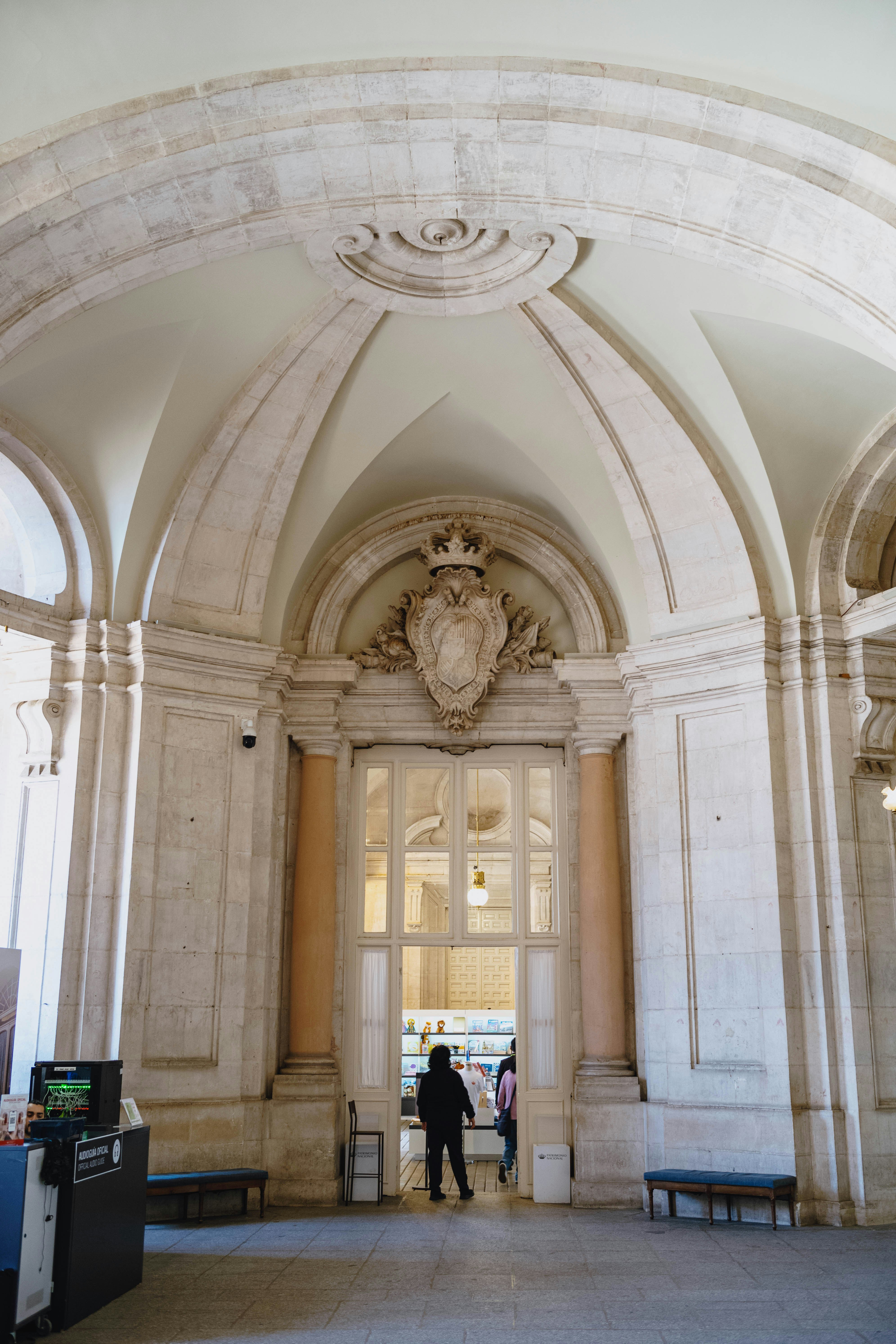 Ornate arched hallway with a decorative crest above a doorway.