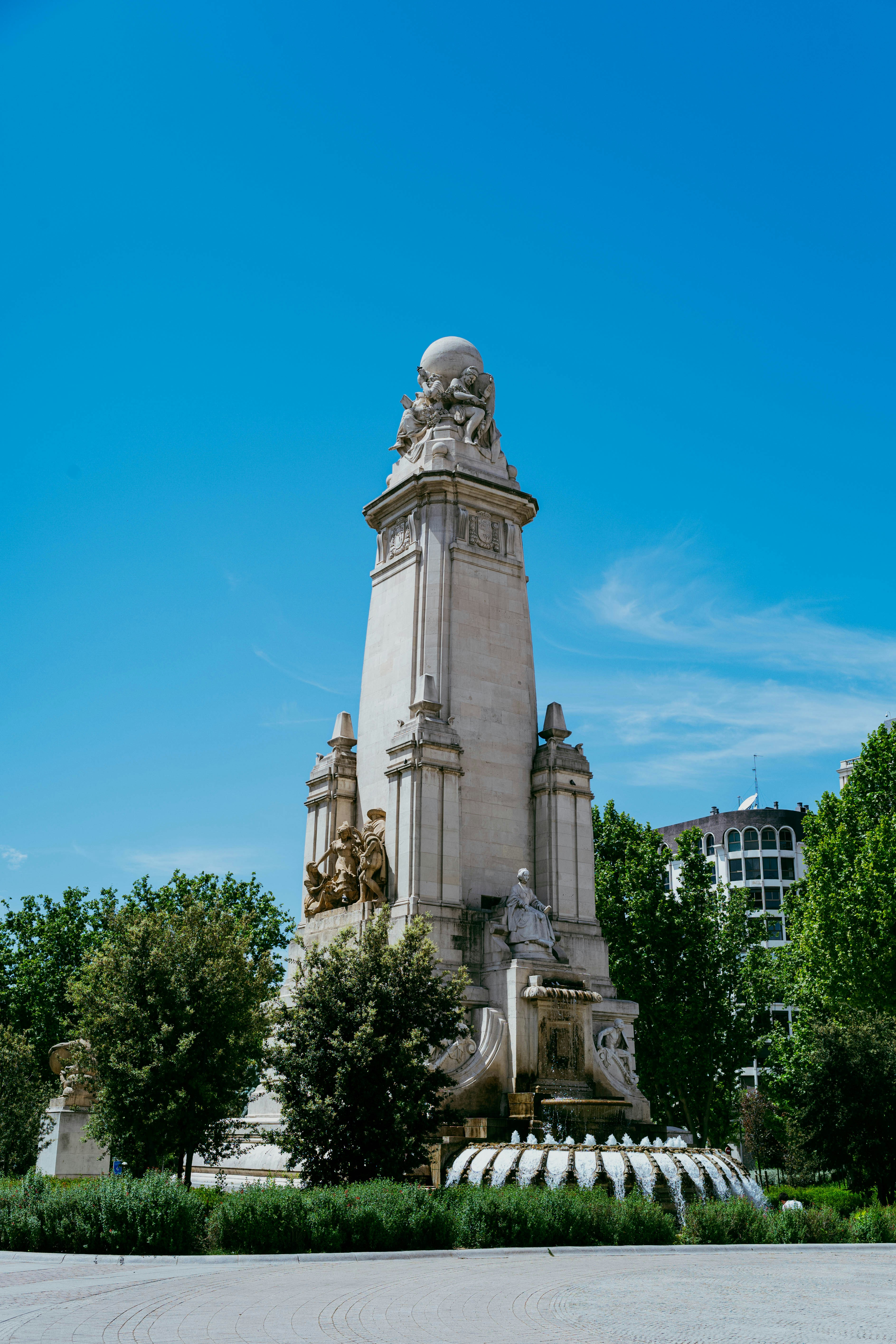 Historic stone monument and fountain against a clear blue sky.