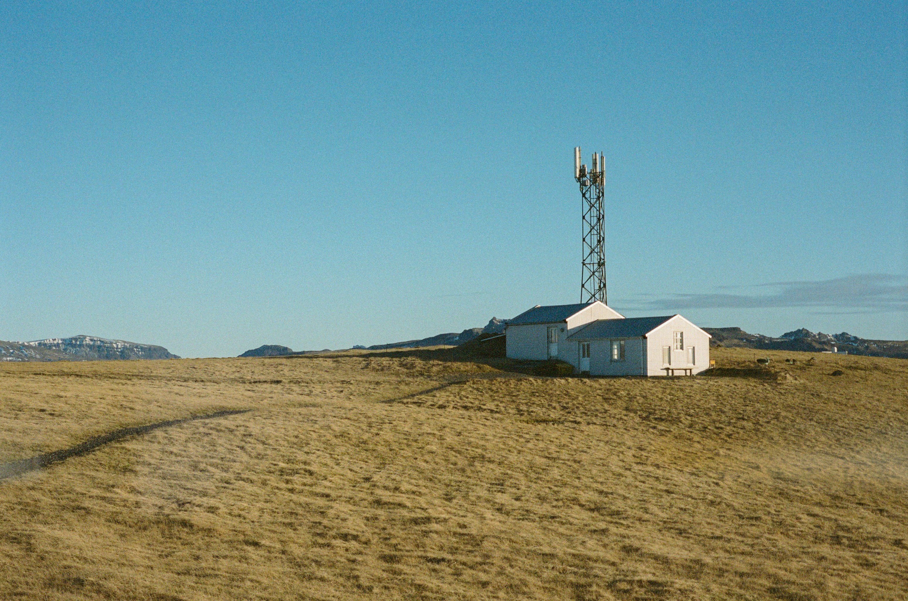 Communication tower with buildings on a golden grassy hill.