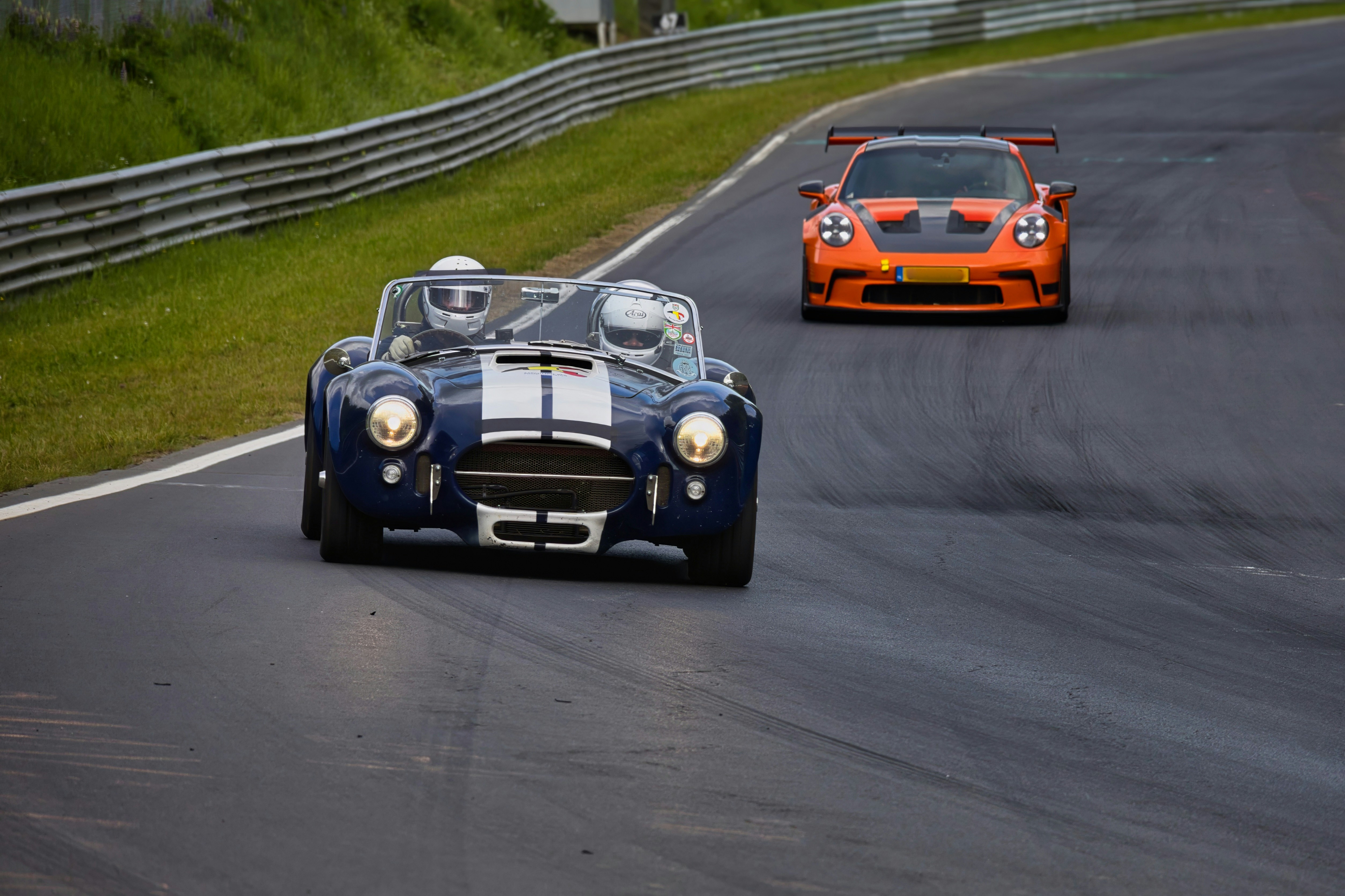 Classic blue and modern orange race cars on a track.