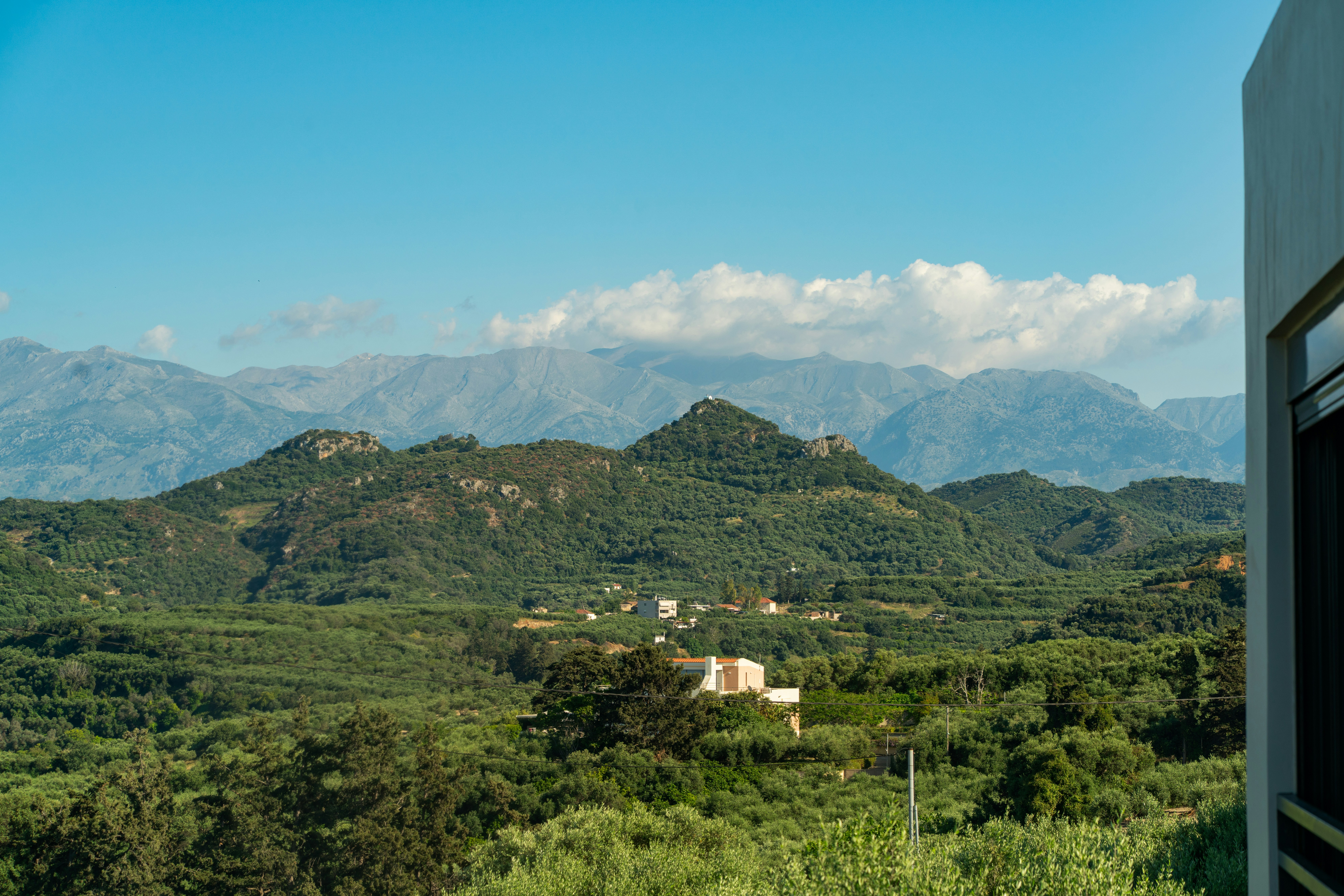 Green hills and distant mountains under a clear blue sky.