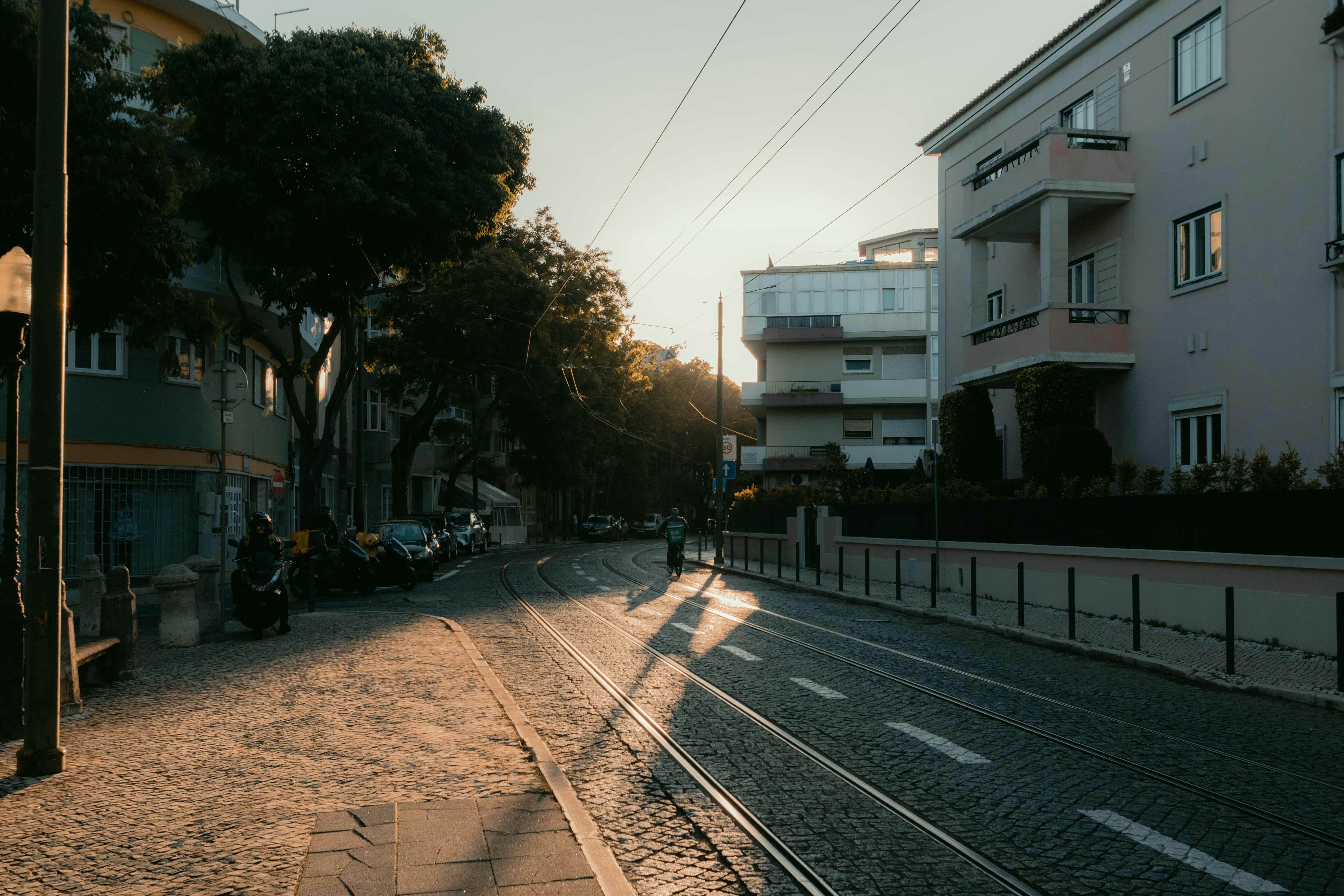 Golden hour light illuminates a city street with tram tracks.