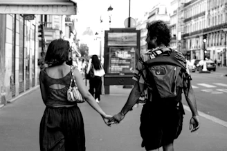 Man and woman holding hands walking on city street.