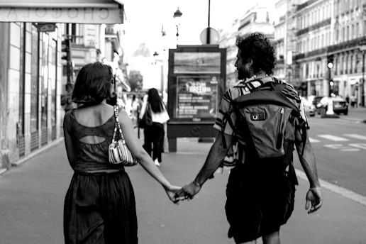 Man and woman holding hands walking on city street.