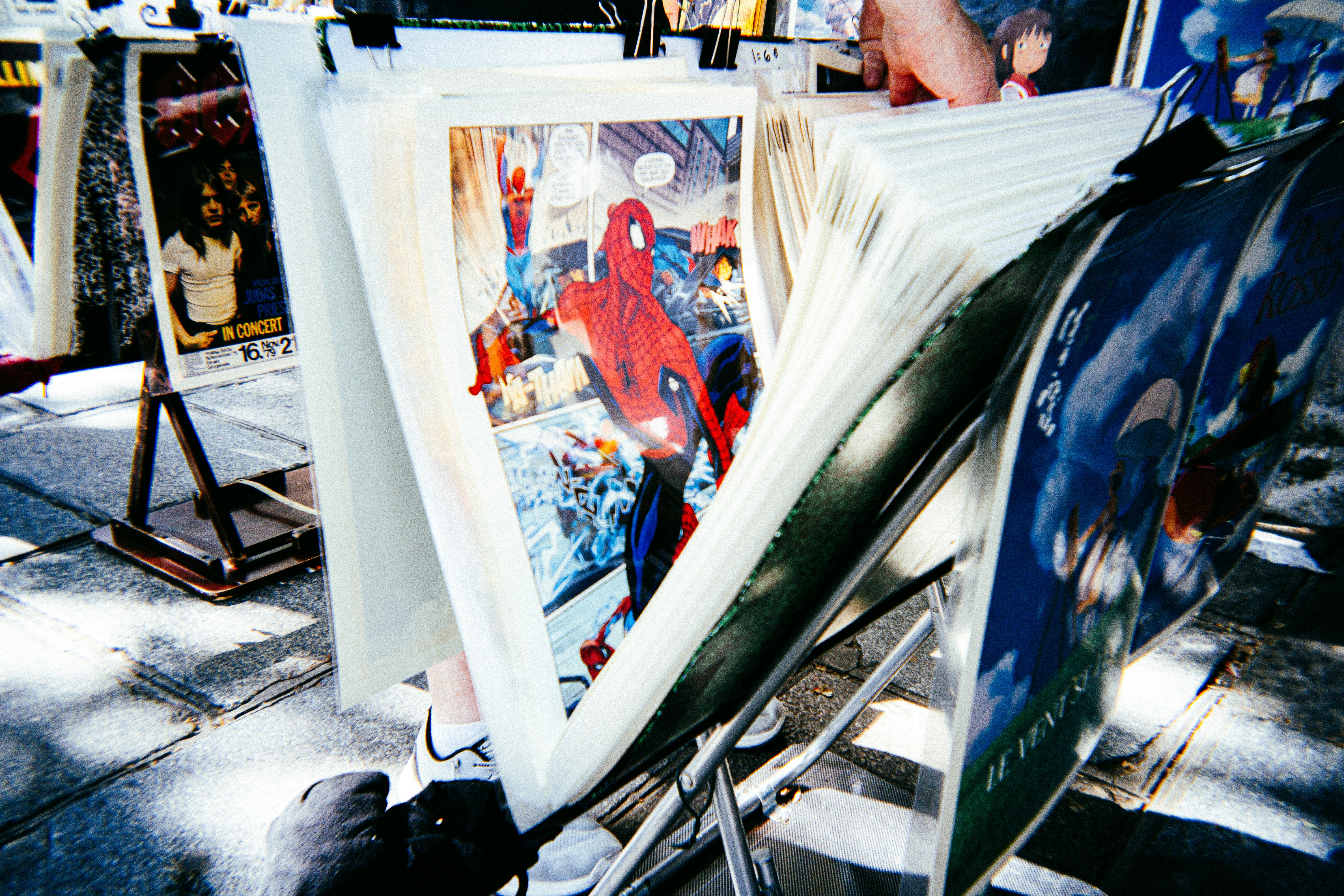 Spider-man print displayed among other artworks at an outdoor stall.
