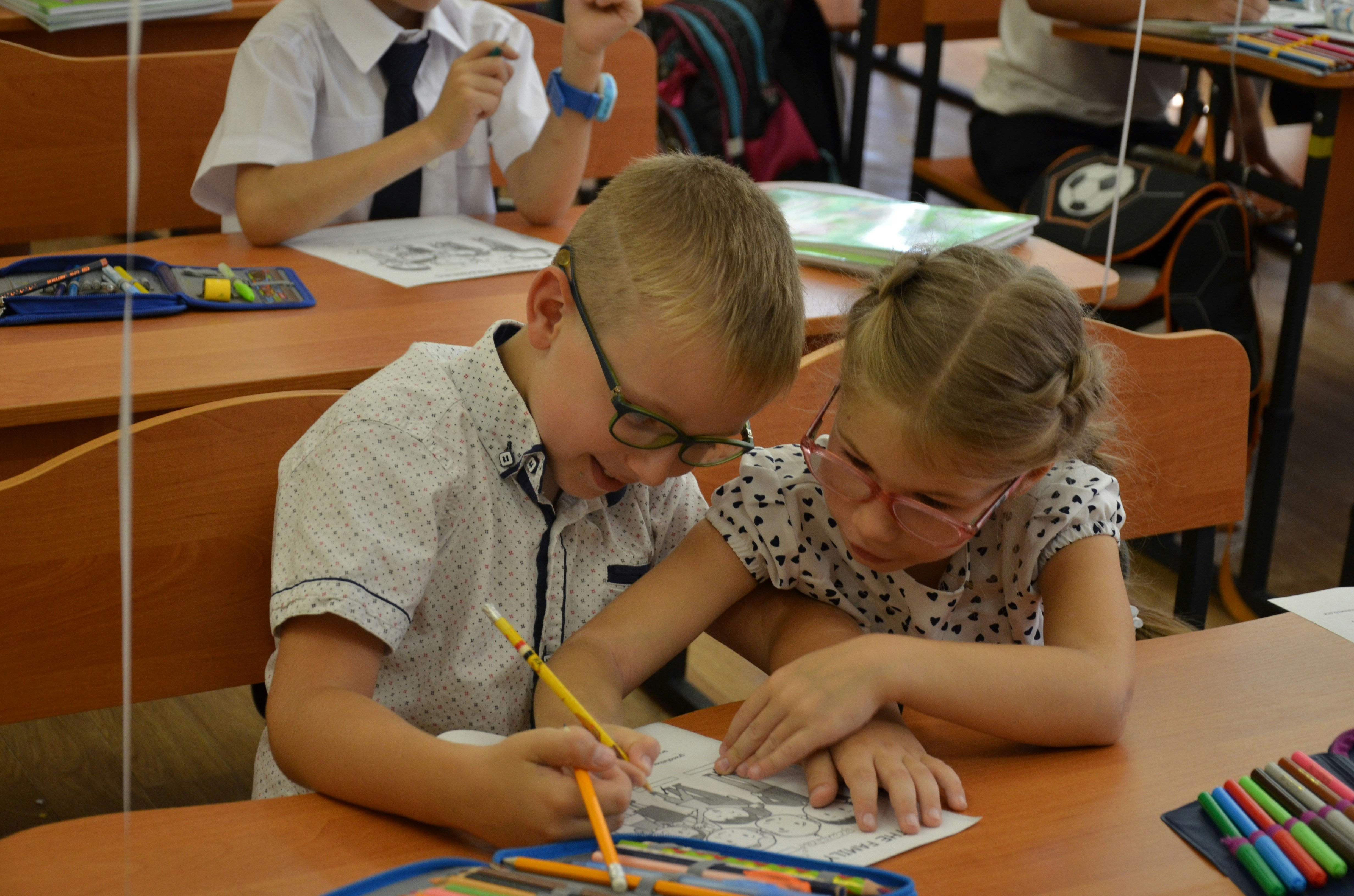 Two diverse elementary school children classmates studying together at desk