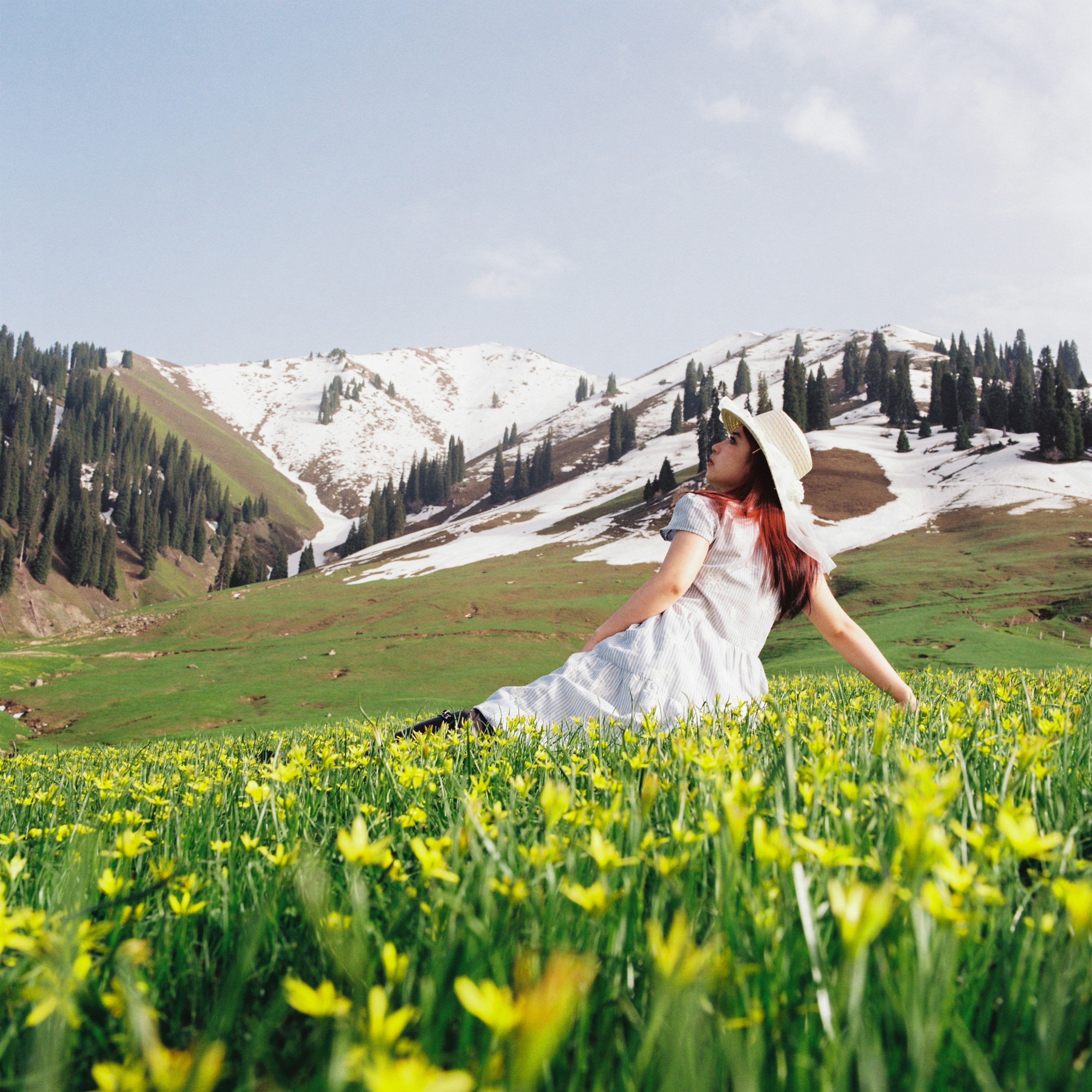 Woman in white dress relaxing in a mountain flower meadow.