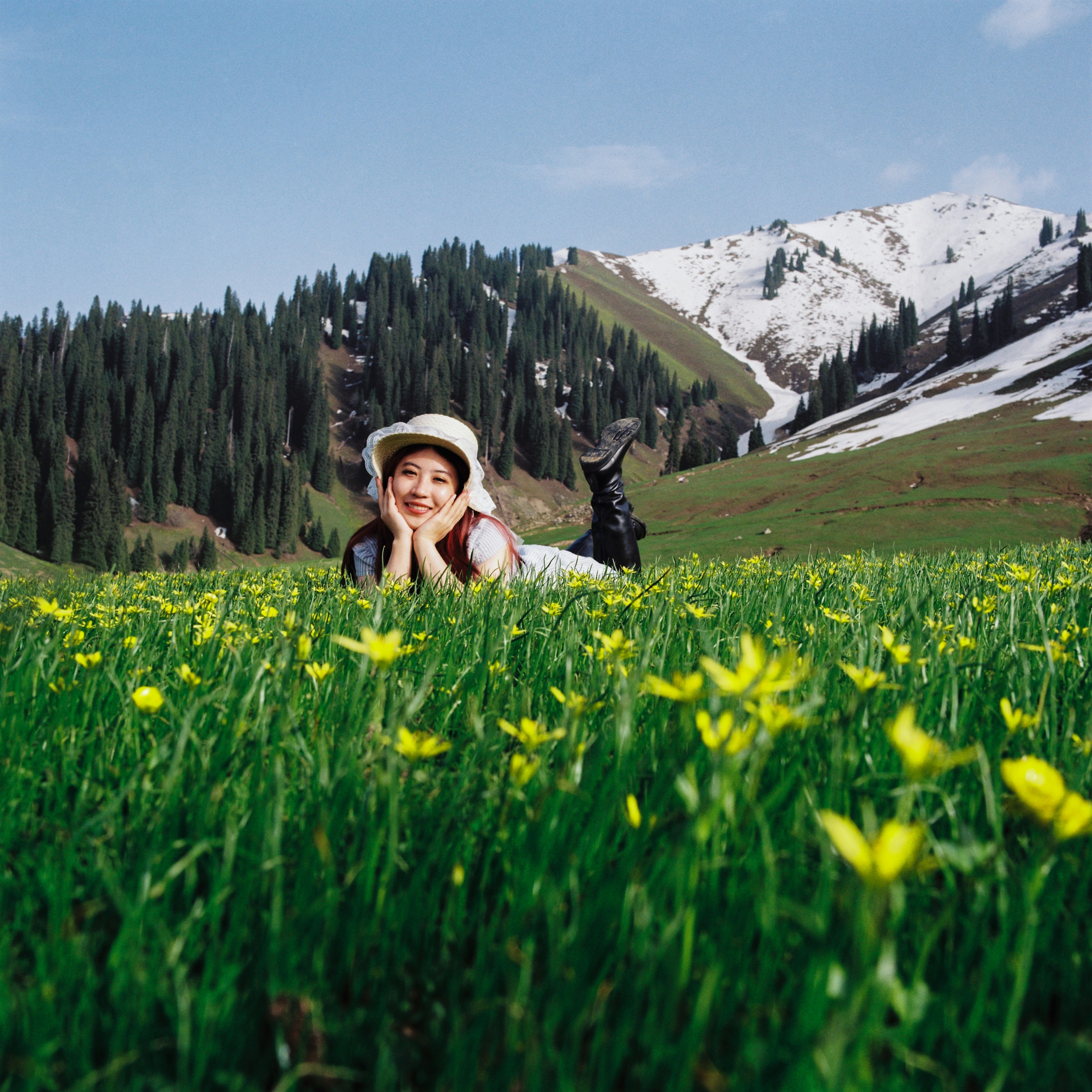 Happy woman in a flower field with snow-capped mountains.