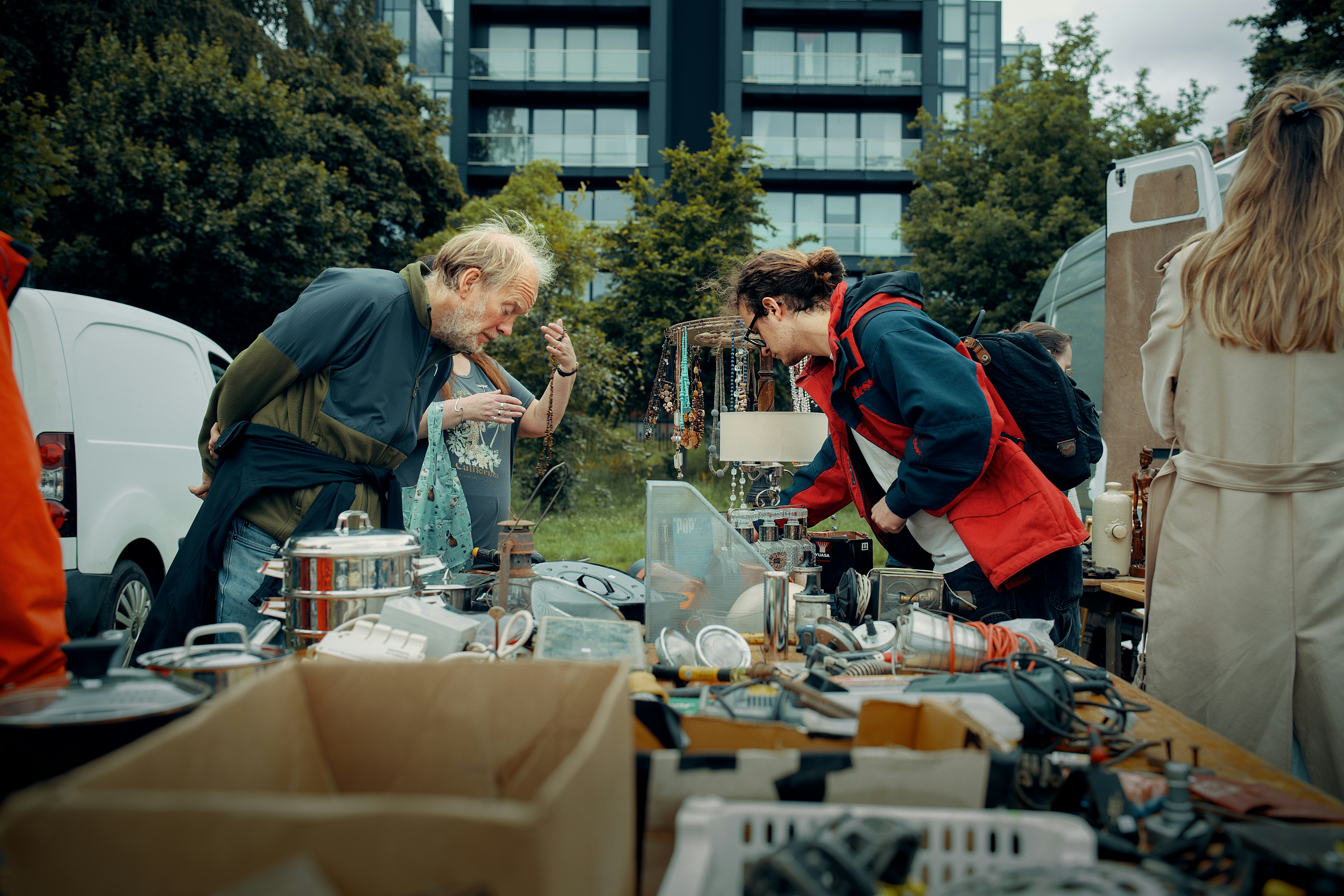 Two people examine goods at an outdoor market stall.
