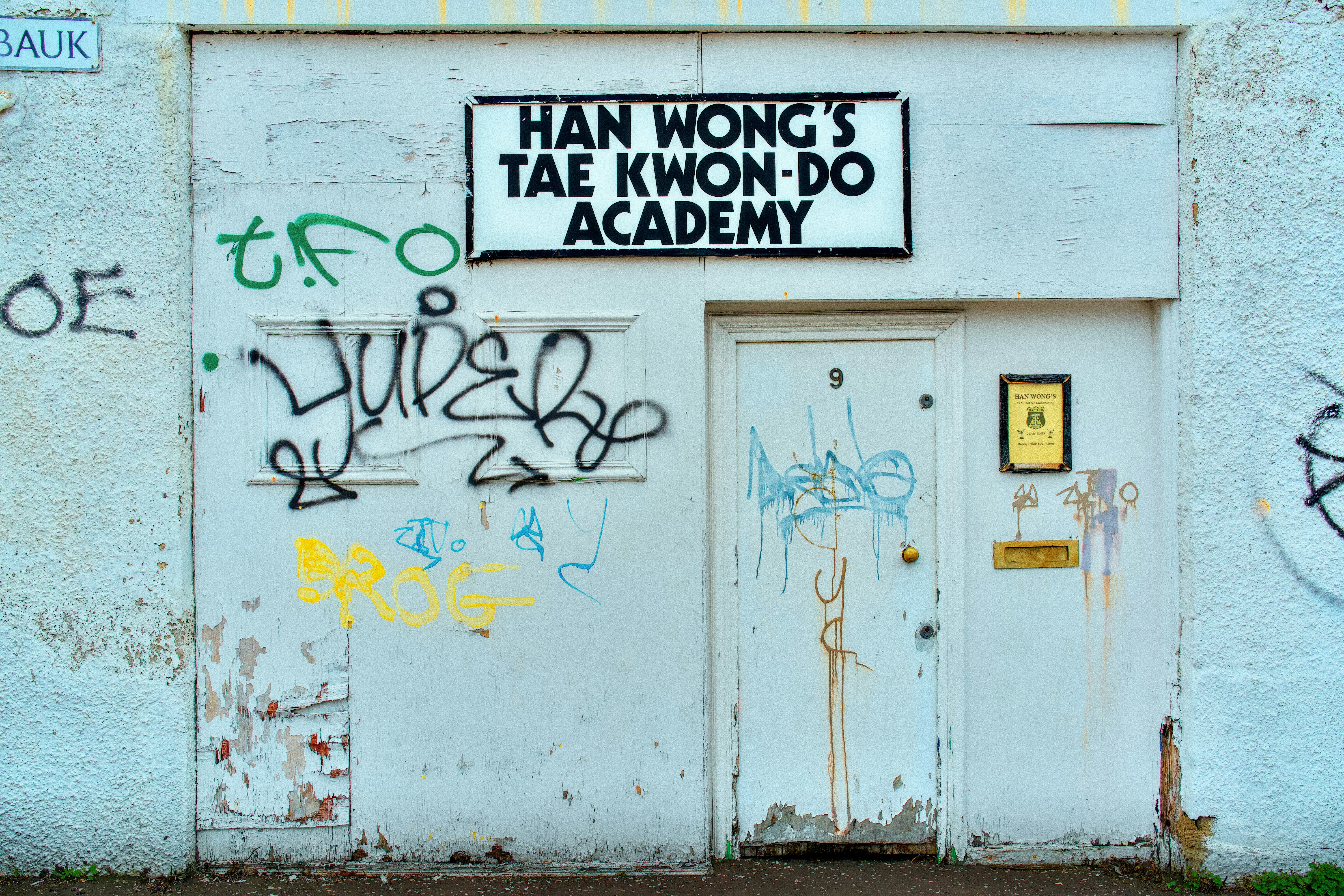 White wall with graffiti and a "tae kwon-do academy" sign.