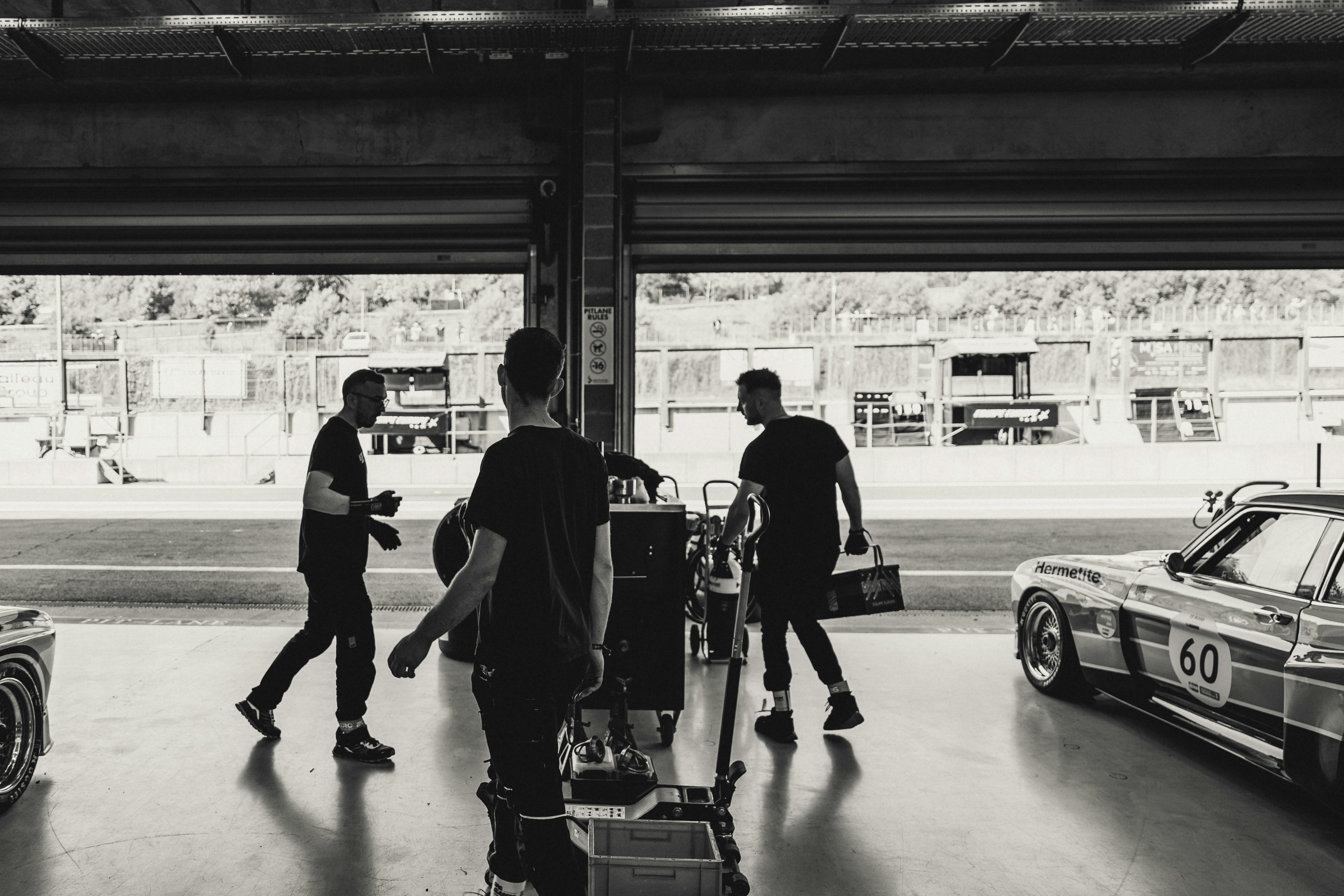 Men and classic race cars in a garage.