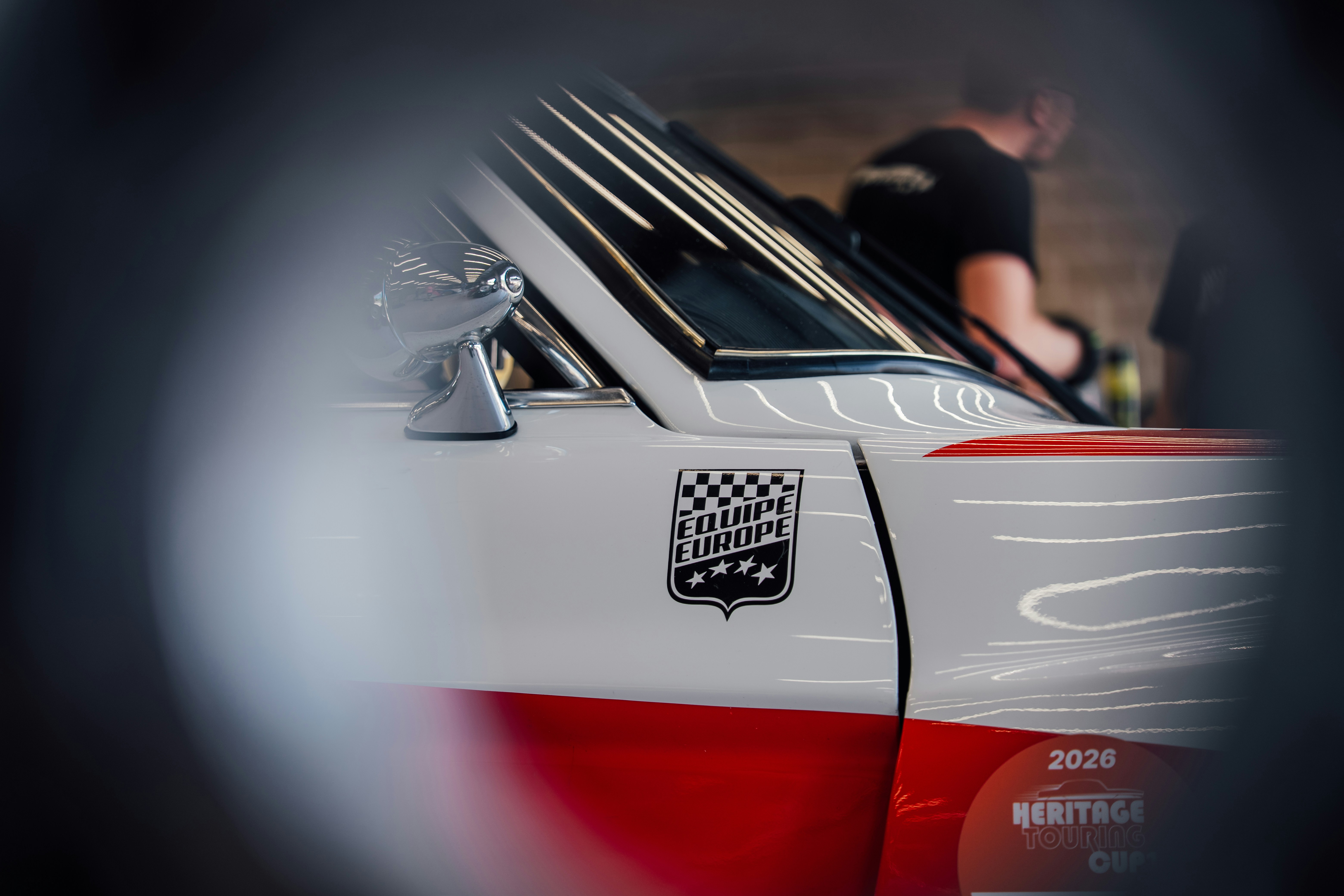 White and red vintage car with a racing emblem.