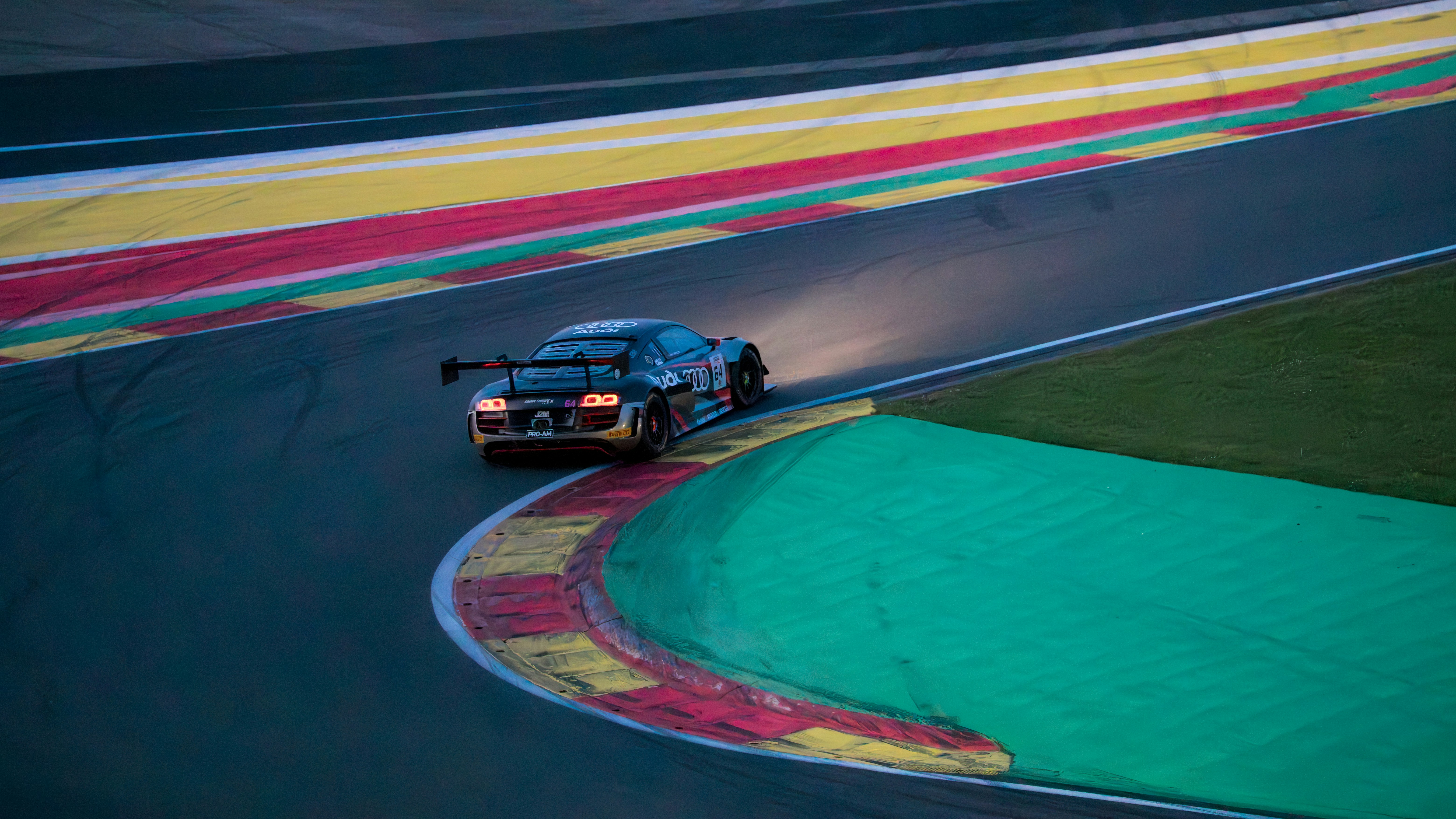 A race car with headlights on a colorful track.
