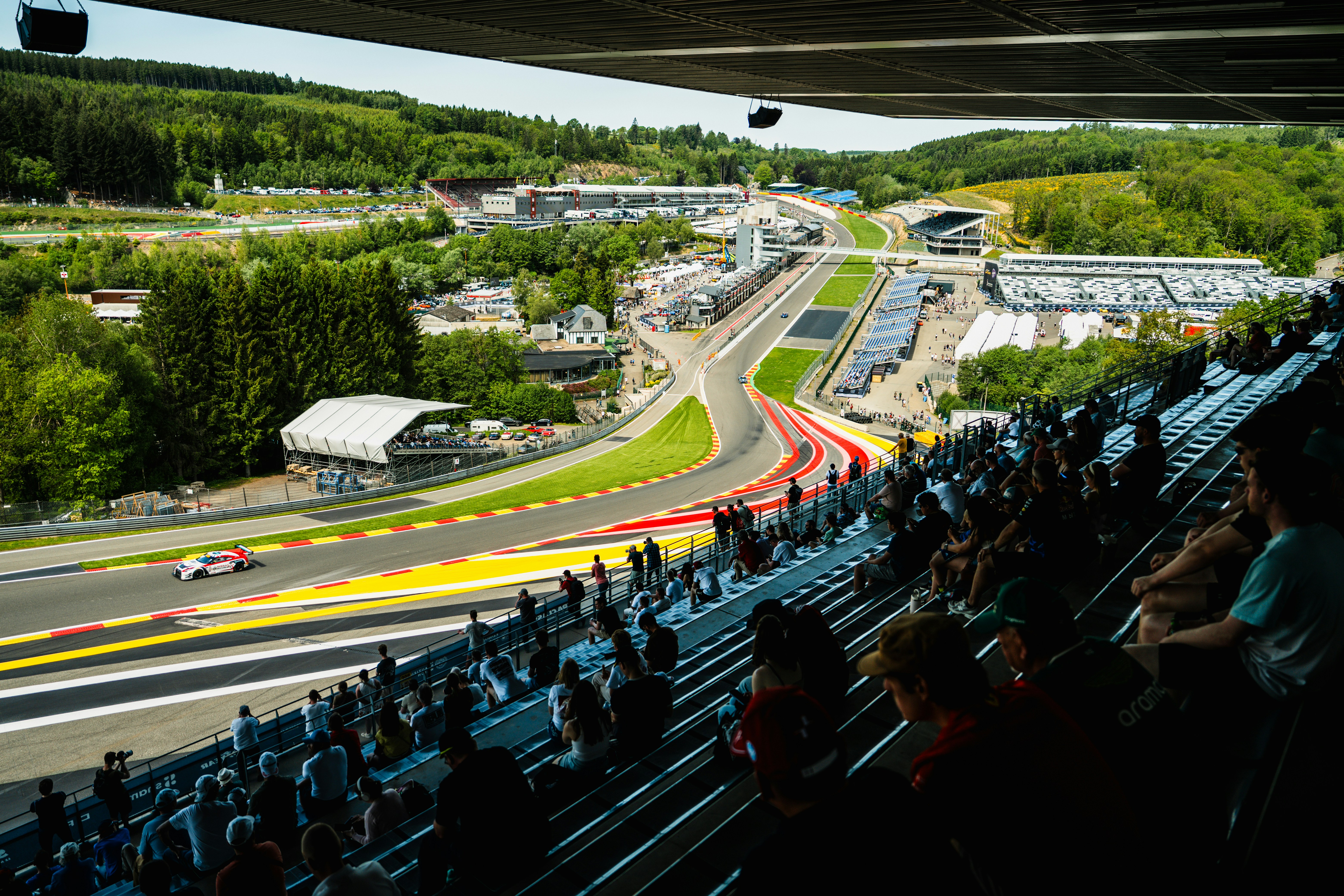 Spectators watch race cars on a winding track.
